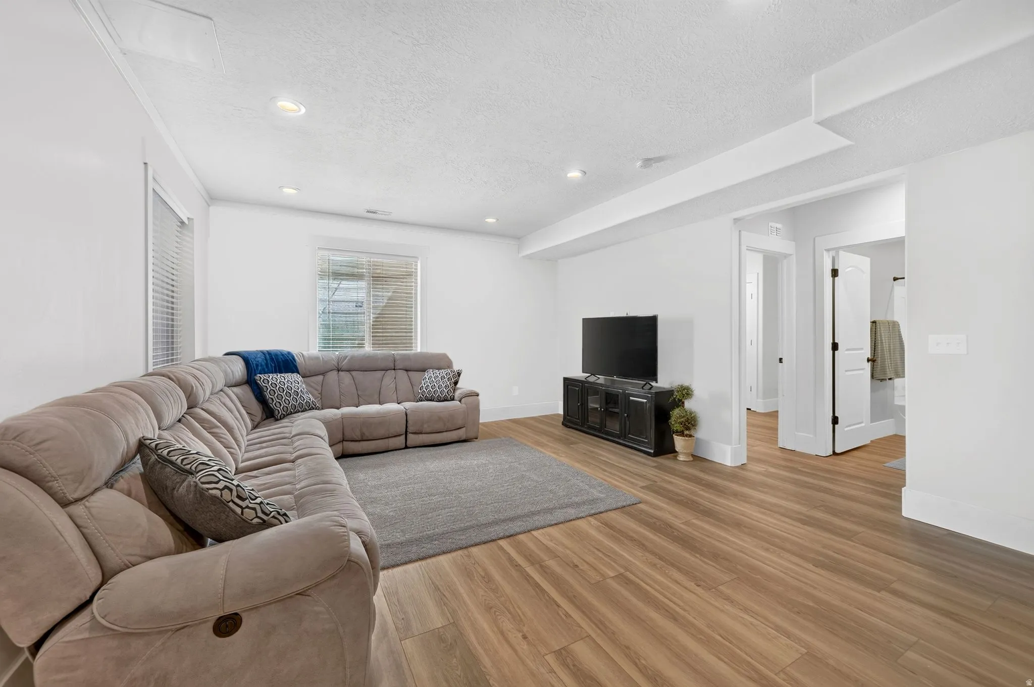Spacious living area featuring wood-finish flooring and recessed lighting