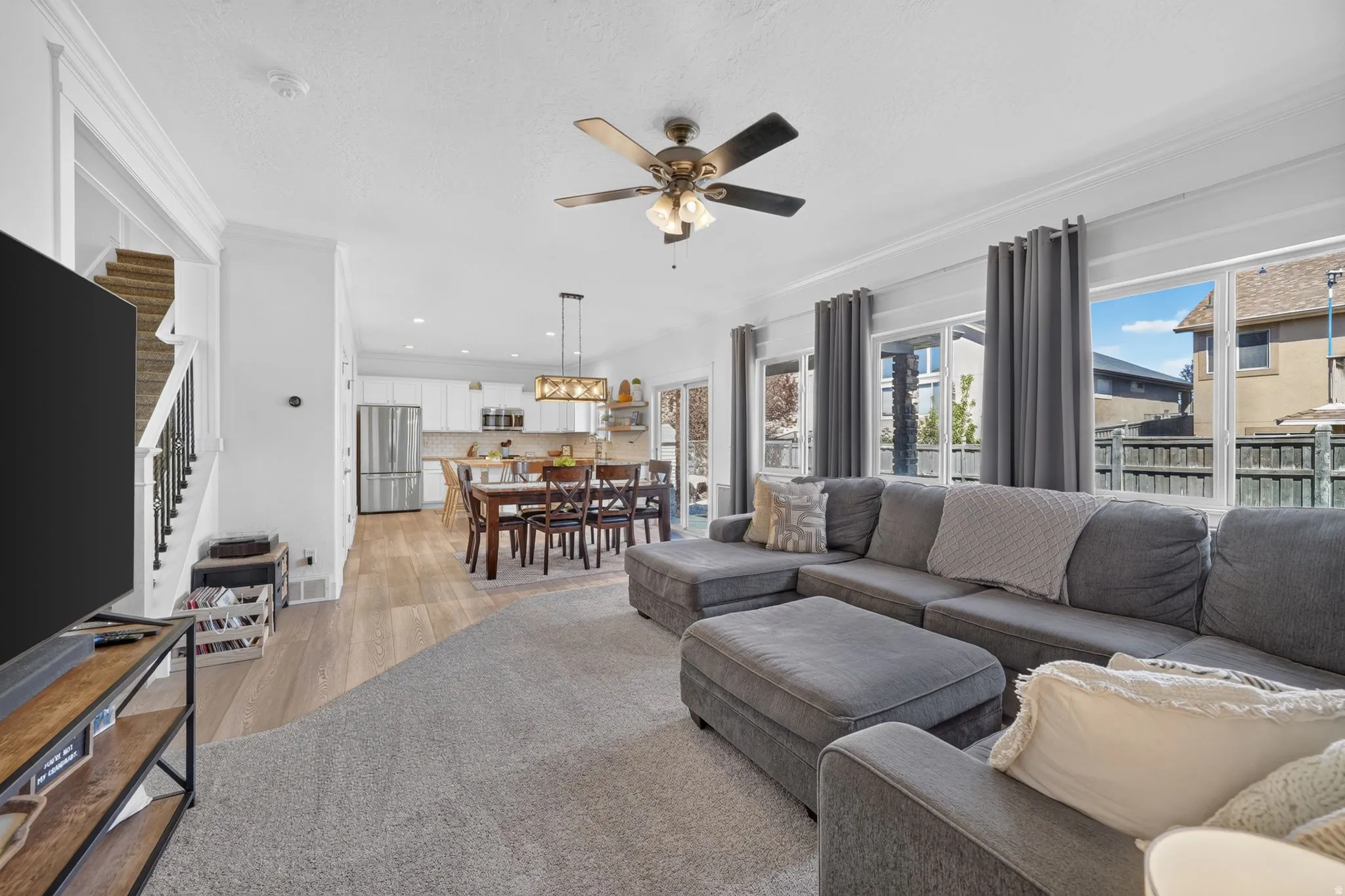 Open-concept living area with light wood-finish flooring extending into the kitchen and dining areas