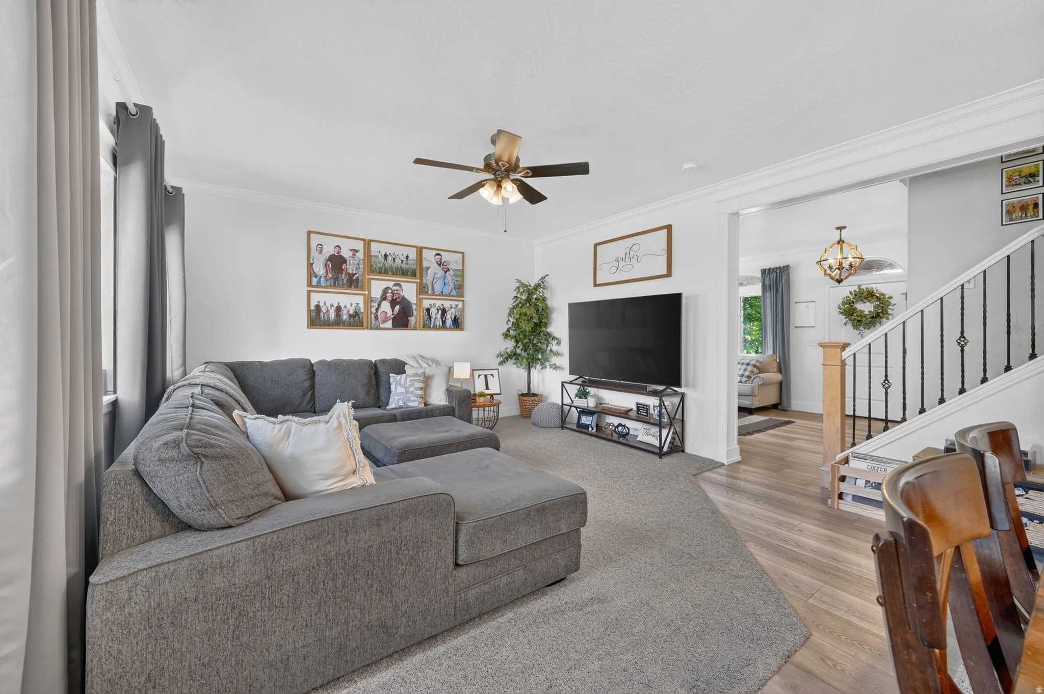 Spacious living area featuring light gray walls, a ceiling fan, and a wide entryway