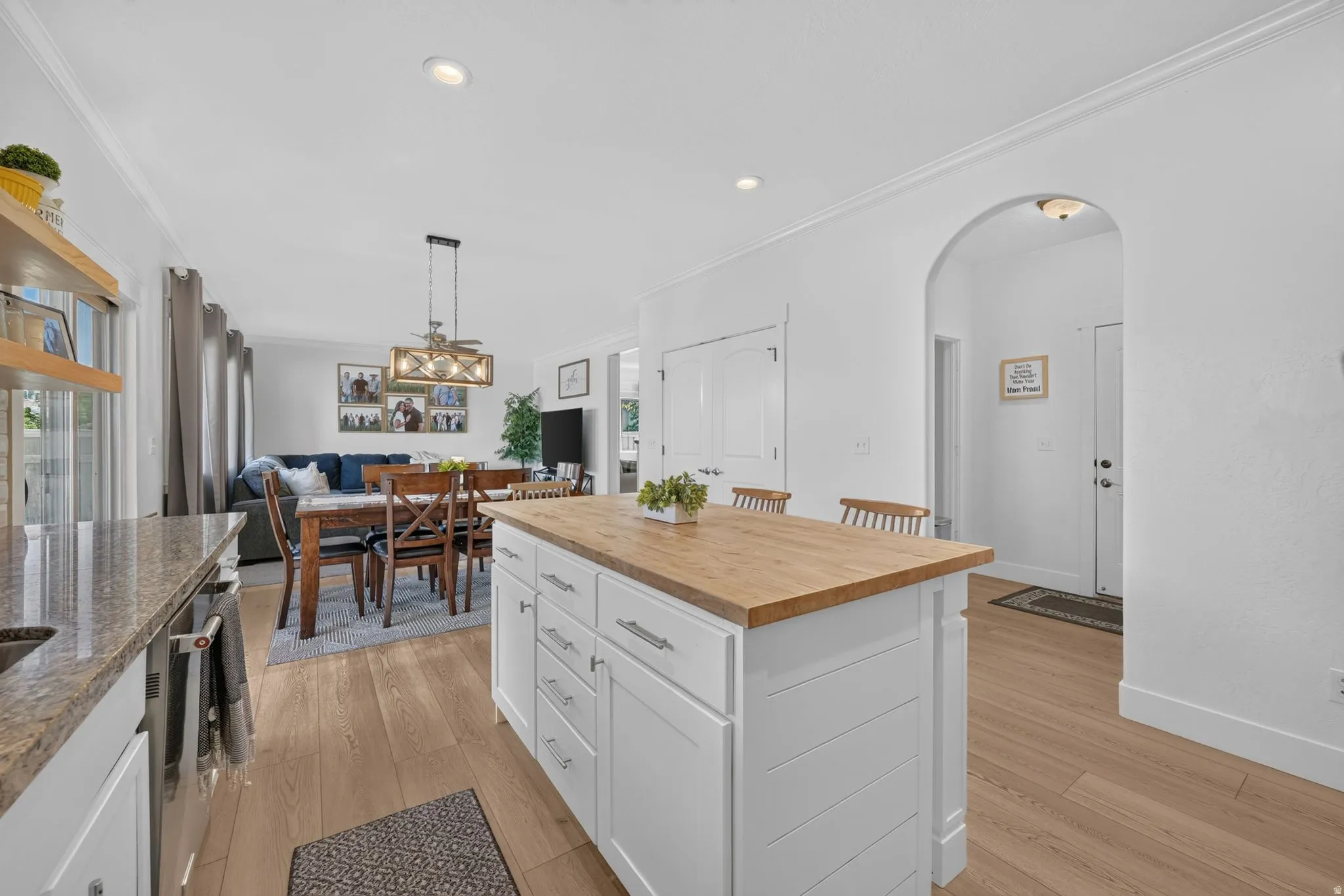Kitchen island featuring a wood-finish countertop and white shaker-style cabinetry with chrome hardware