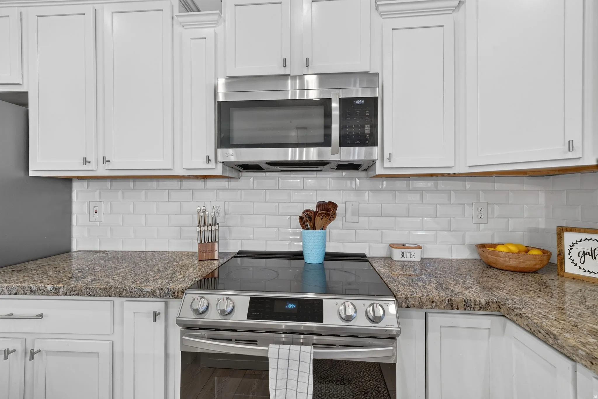 Kitchen featuring white shaker-style cabinetry, a white subway tile backsplash, and granite countertops
