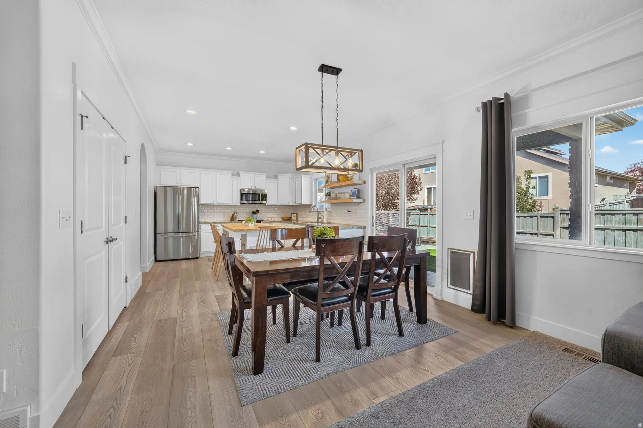 Open-concept dining area featuring wood-finish flooring, a contemporary chandelier, and direct access to the outdoor space via sliding glass doors