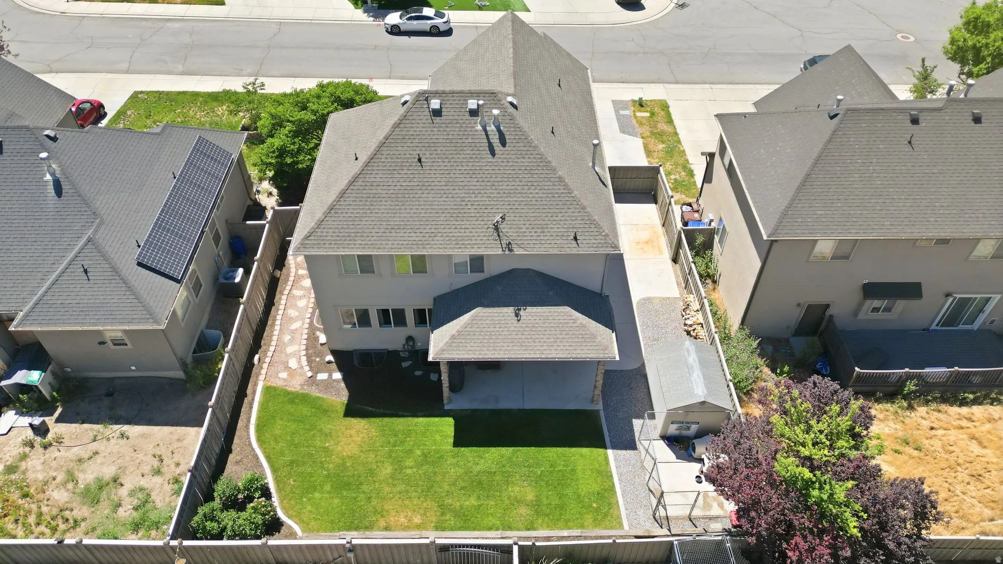 Rear exterior featuring a covered patio, expansive lawn, and fenced perimeter
