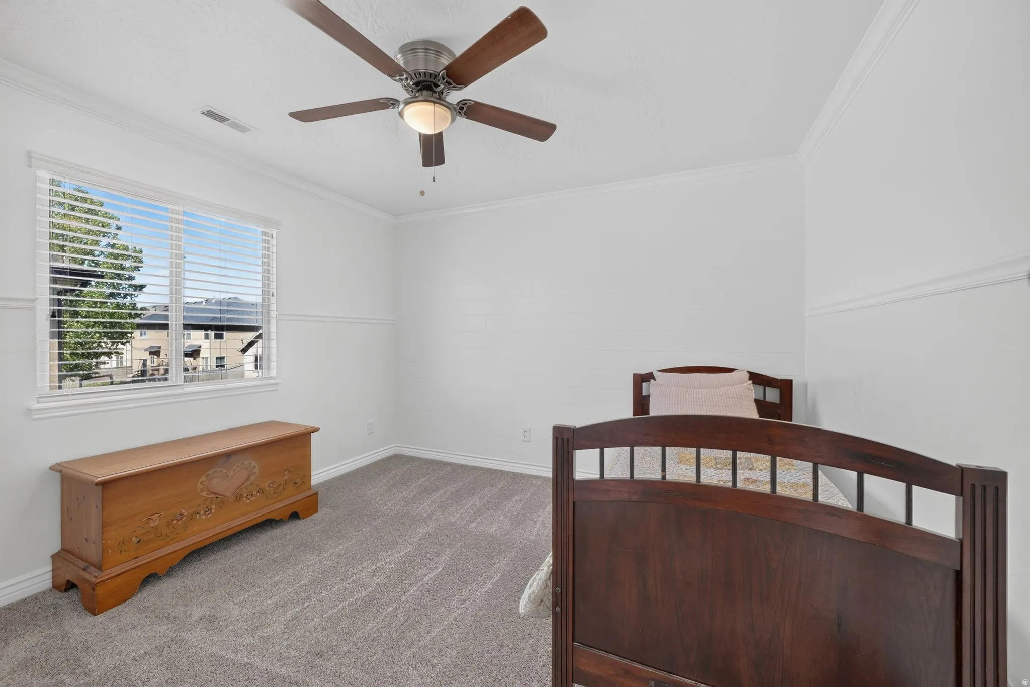 Carpeted room featuring a white window frame with horizontal blinds, a ceiling fan with integrated lighting, crown molding, and white baseboards