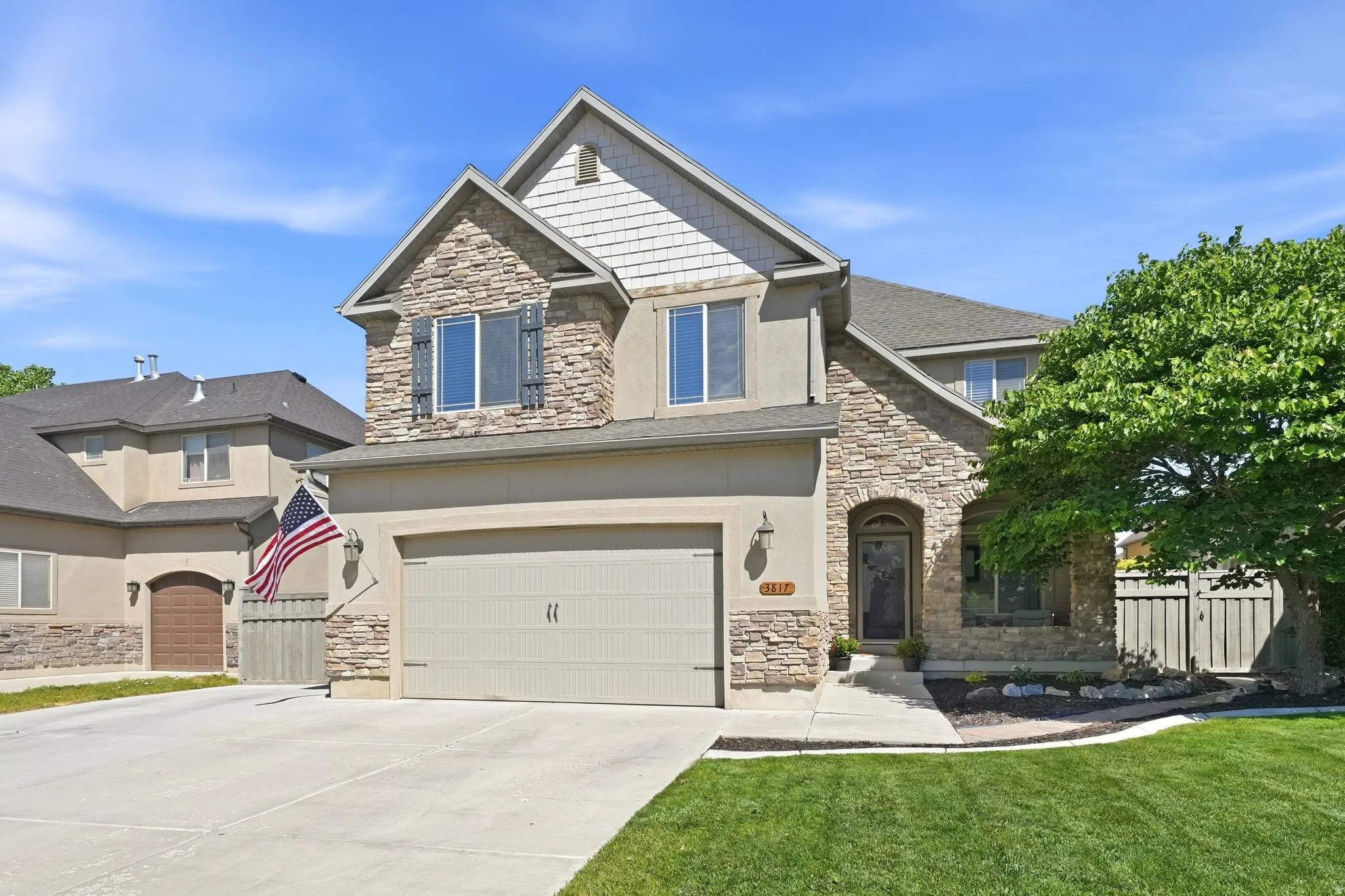 Multi-level residence featuring stone and stucco exterior, an arched entry, and a prominent attached two-car garage