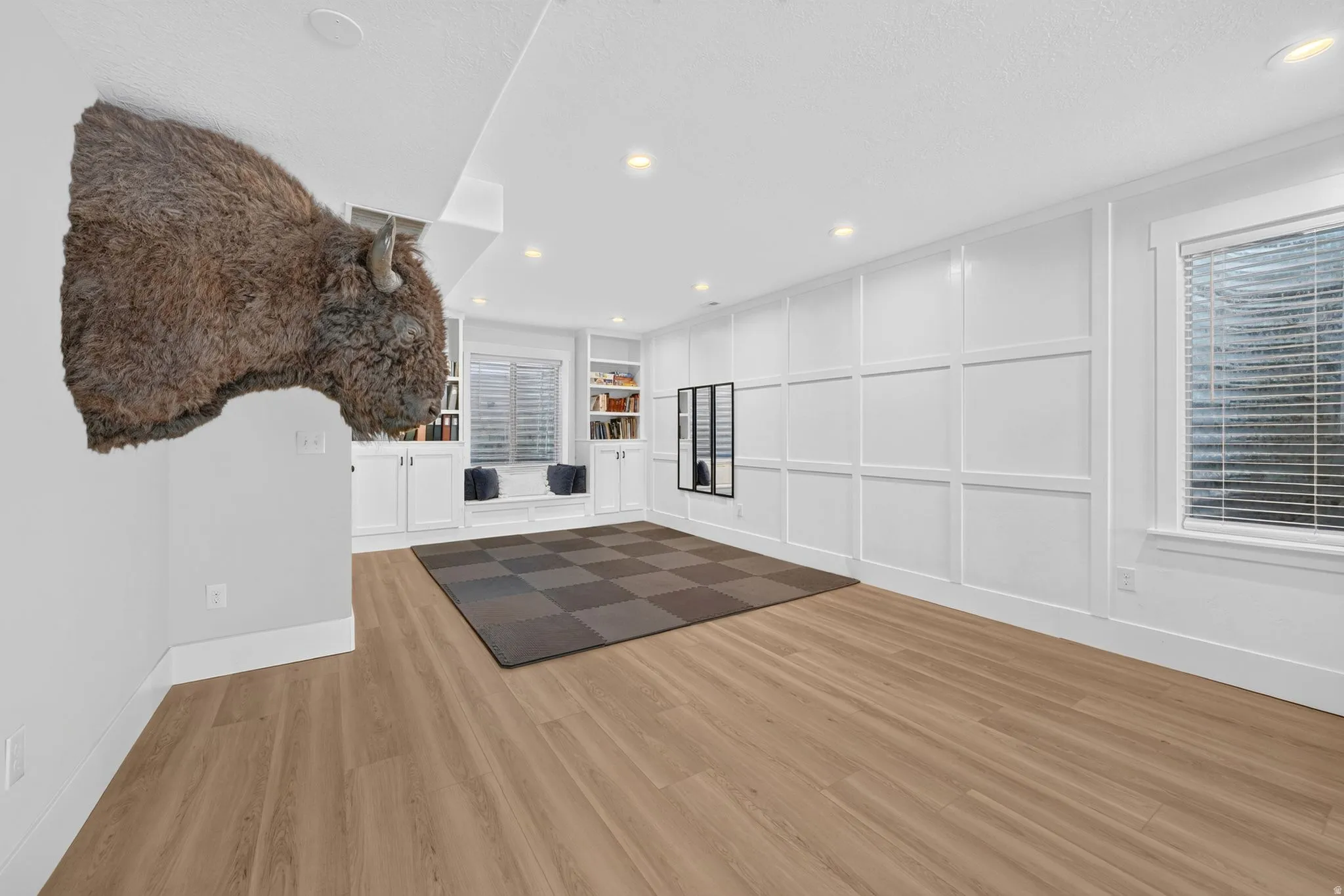 Spacious interior room featuring wood-finish flooring, recessed lighting, and white wainscoting