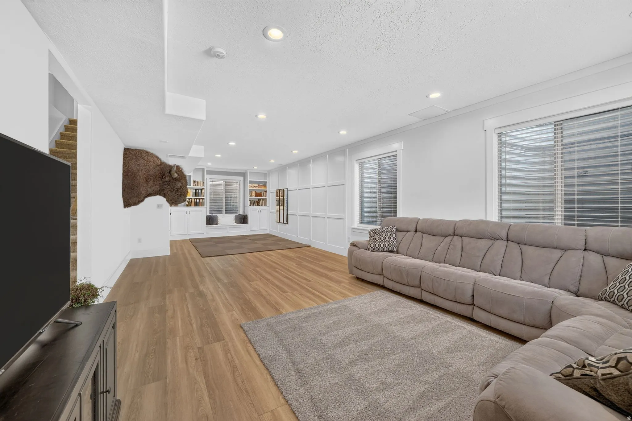 Spacious room featuring wood-finish flooring, recessed lighting, and white paneled walls