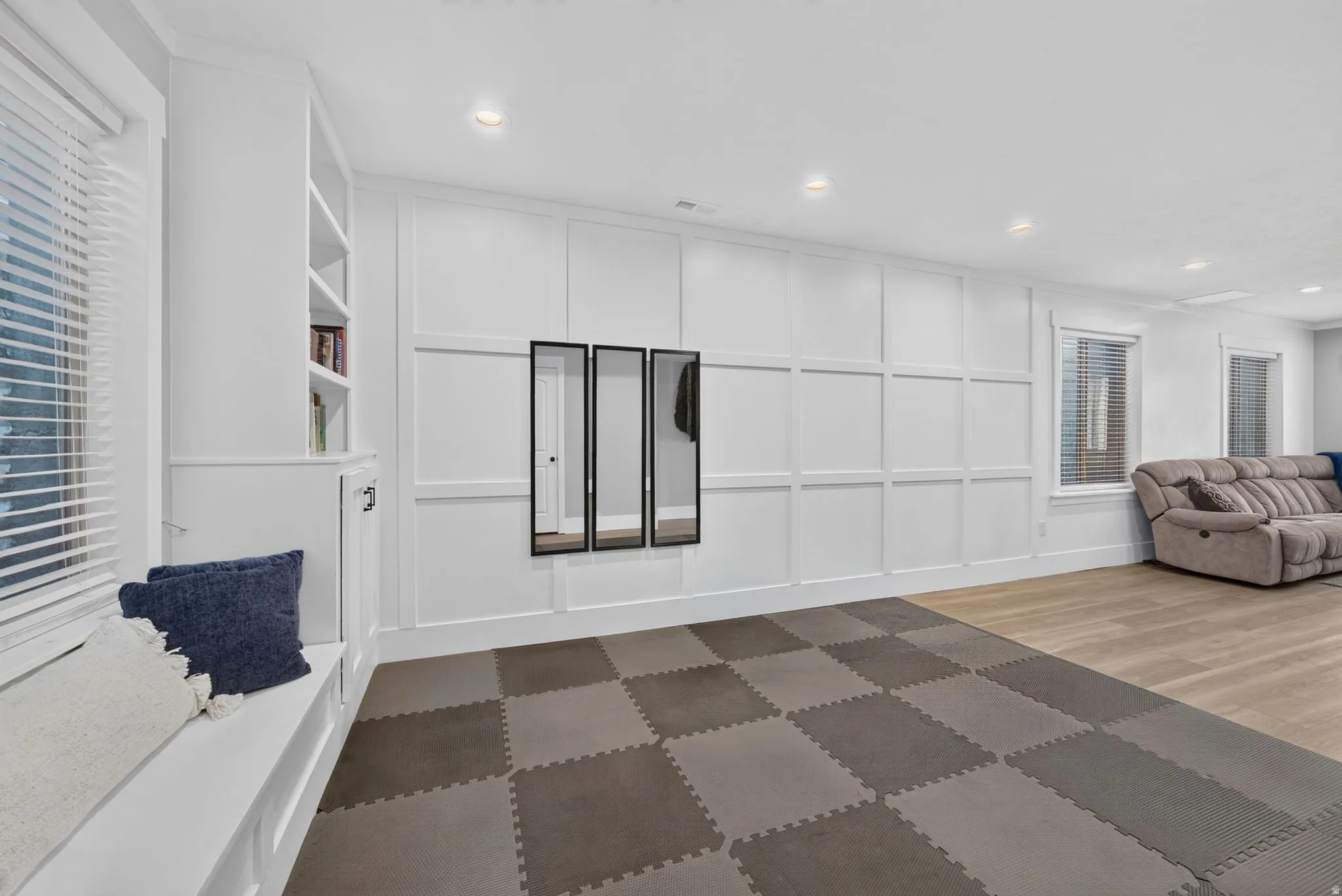 Spacious room featuring paneled walls, recessed lighting, and a built-in window bench with integrated shelving
