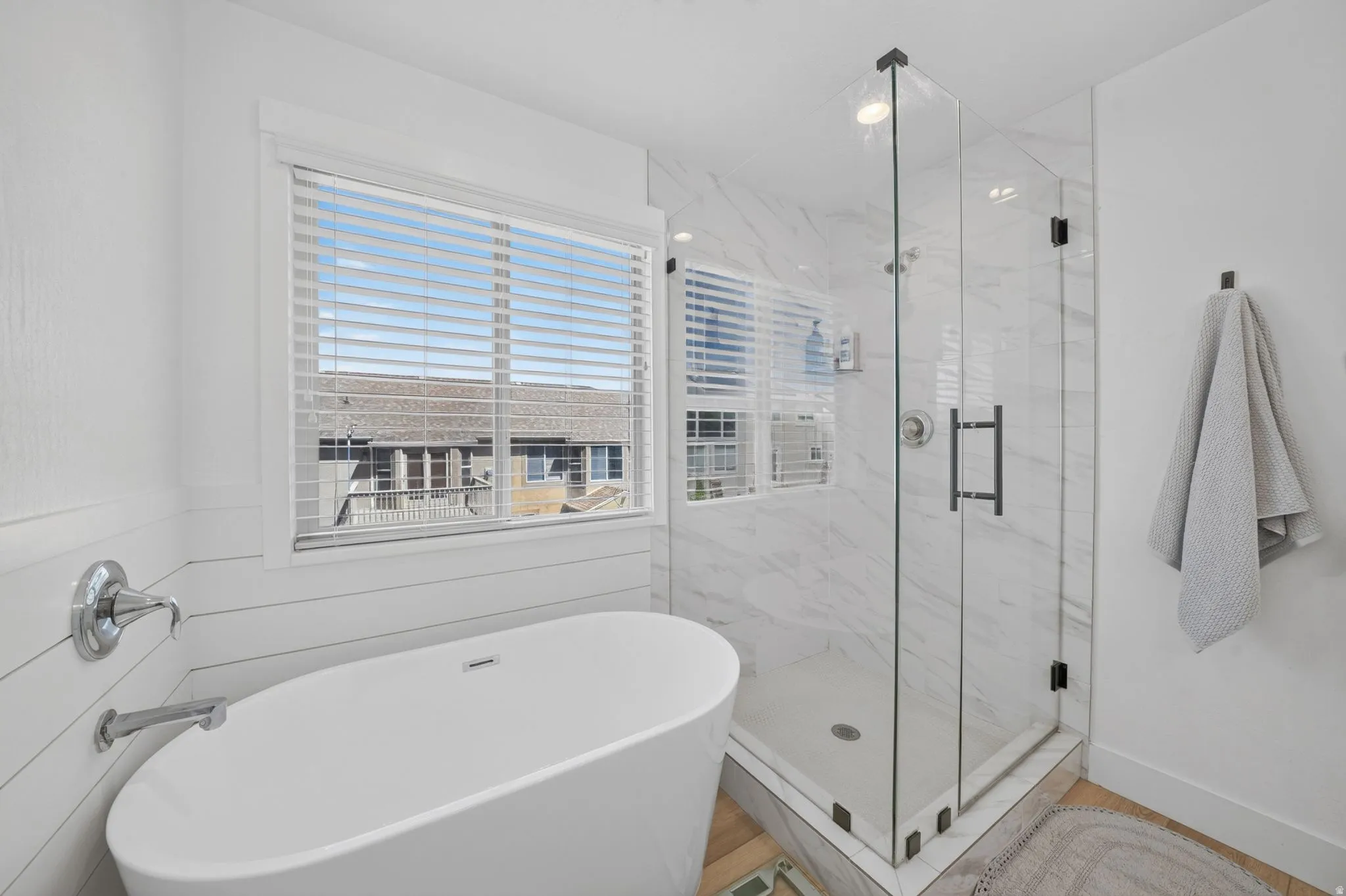 Contemporary bathroom featuring a freestanding soaking tub, glass-enclosed shower with tiled walls, and shiplap paneling