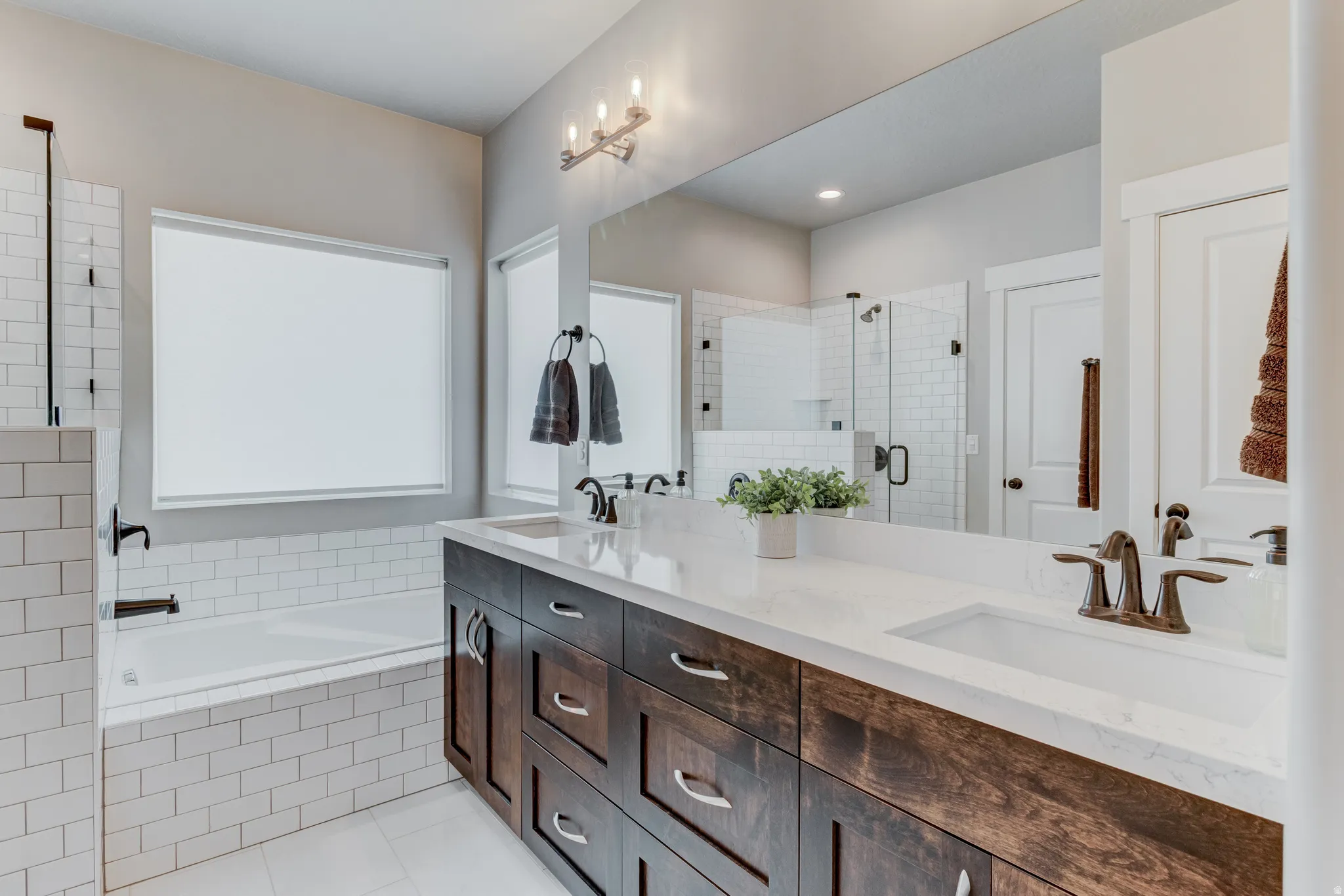 Double vanity featuring wood-finish cabinetry, white countertops, and bronze-finish fixtures