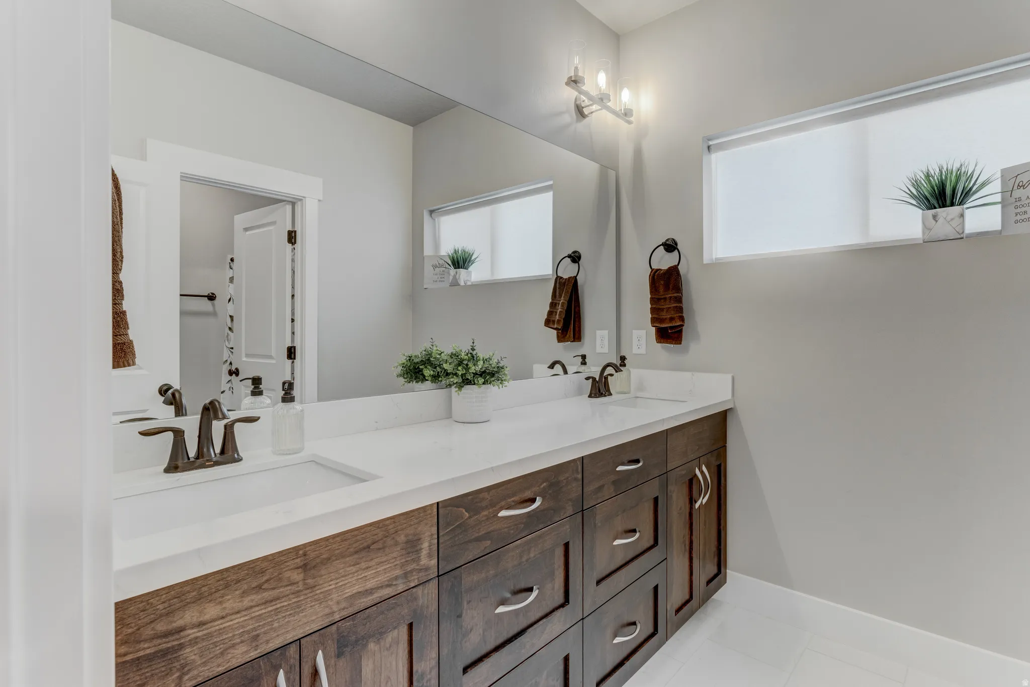 Dual vanity with dark wood-finish cabinetry, white countertops, and integrated rectangular sinks