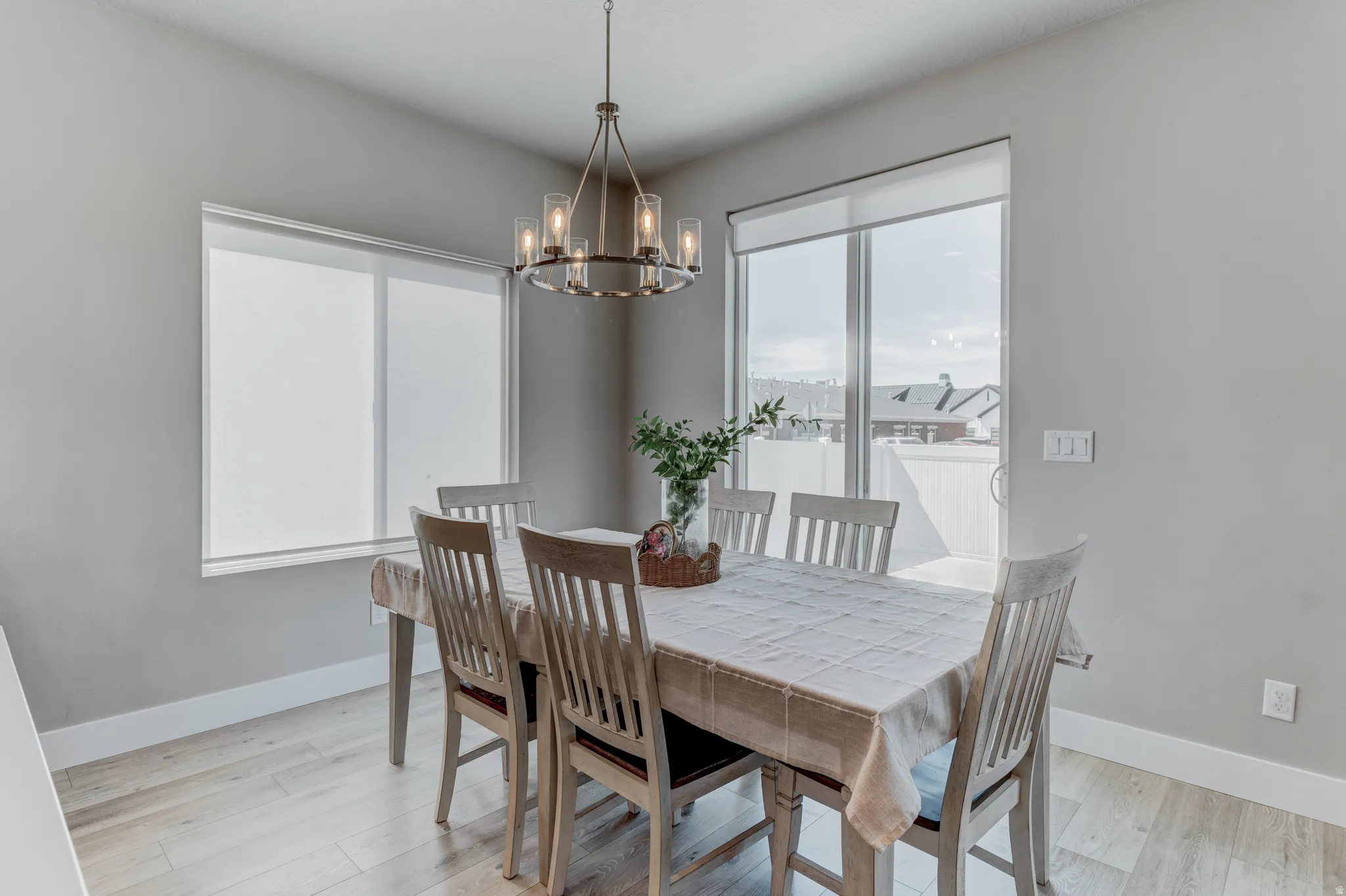 Dining area featuring light wood-finish flooring, a contemporary chandelier, a sliding glass door, and a large window