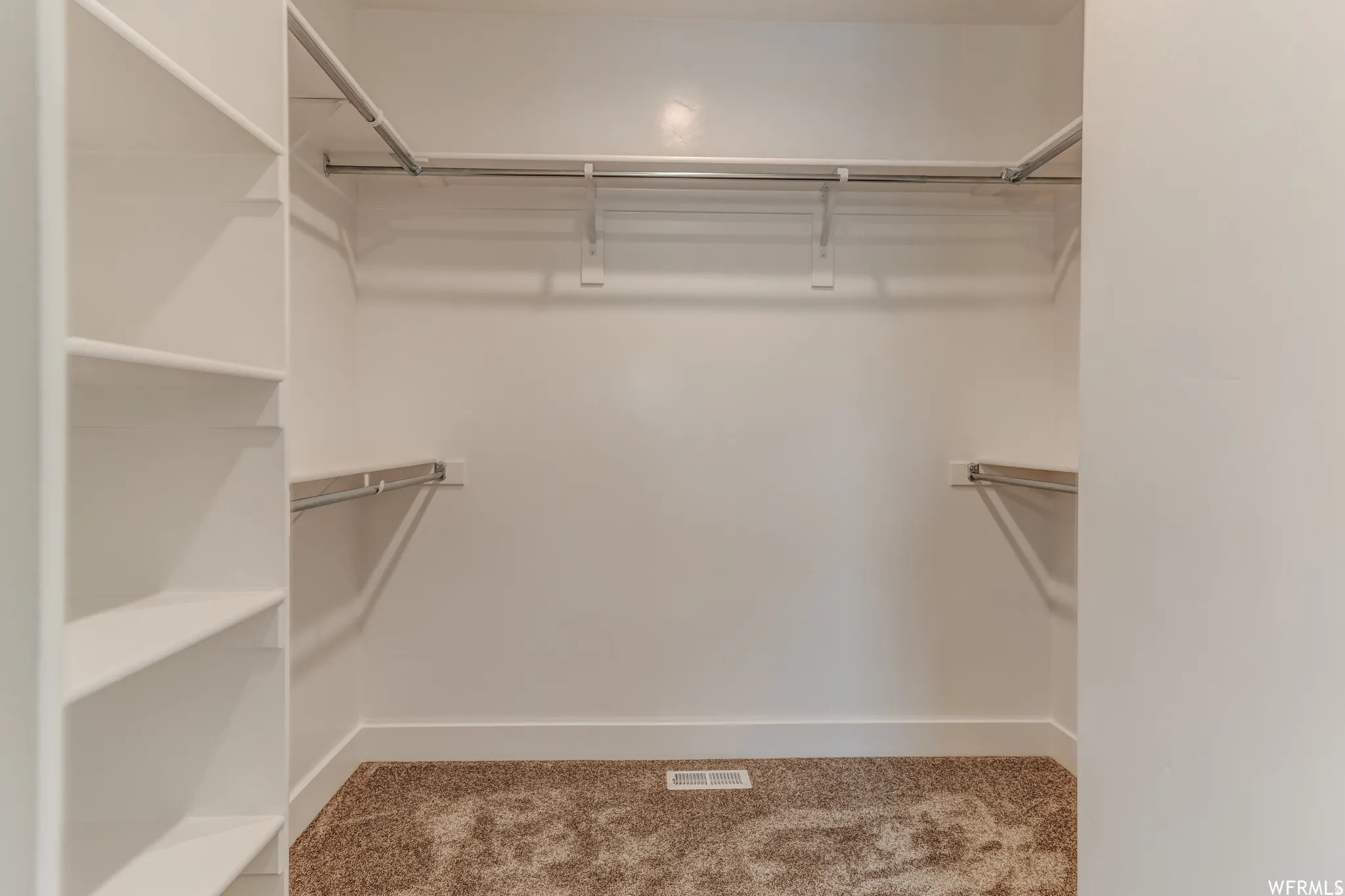 Built-in shelving, multiple hanging rods, and textured carpeting