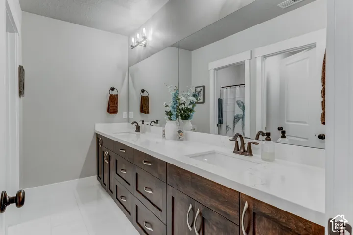 Dual vanity featuring white countertops, undermount sinks, and wood-finish cabinetry with brushed nickel hardware