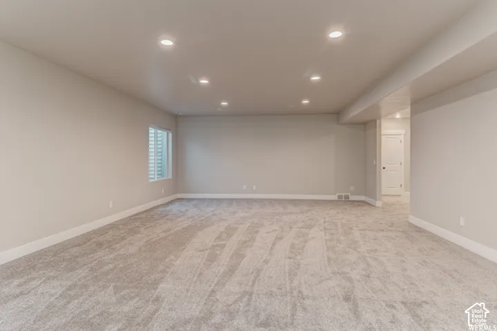 Spacious carpeted room featuring recessed lighting, a single window, and neutral-toned walls