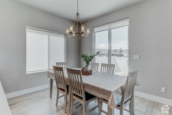 Dining area featuring light wood-finish flooring, a contemporary chandelier, a sliding glass door, and a large window