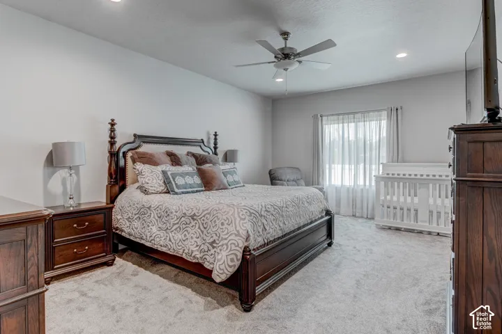 Spacious bedroom featuring light-toned carpeting, recessed lighting, and a ceiling fan