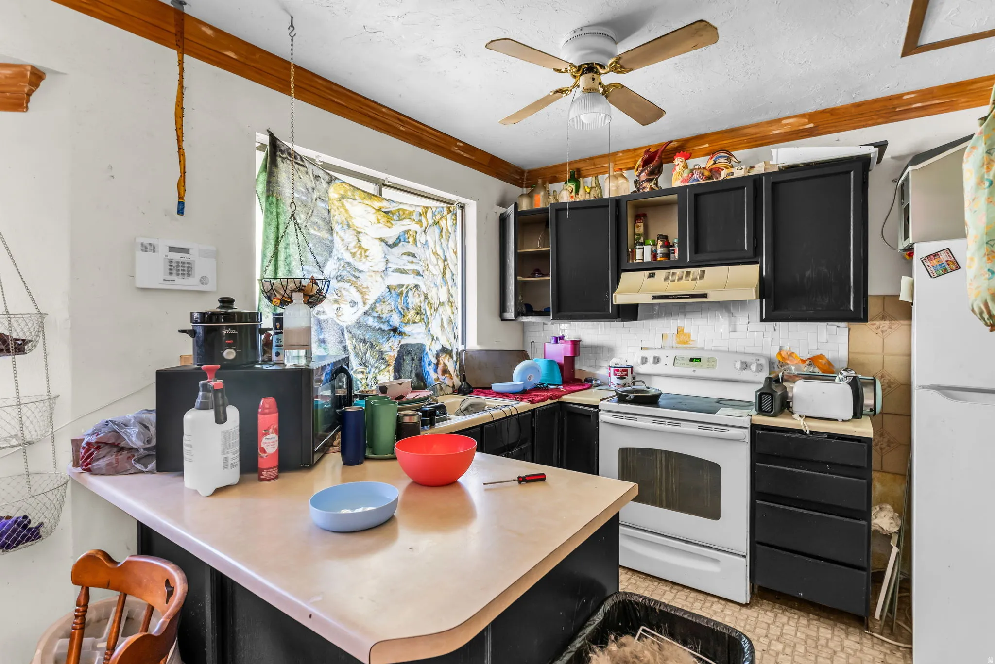 Kitchen featuring a ceiling fan, black cabinetry, white range, and a window