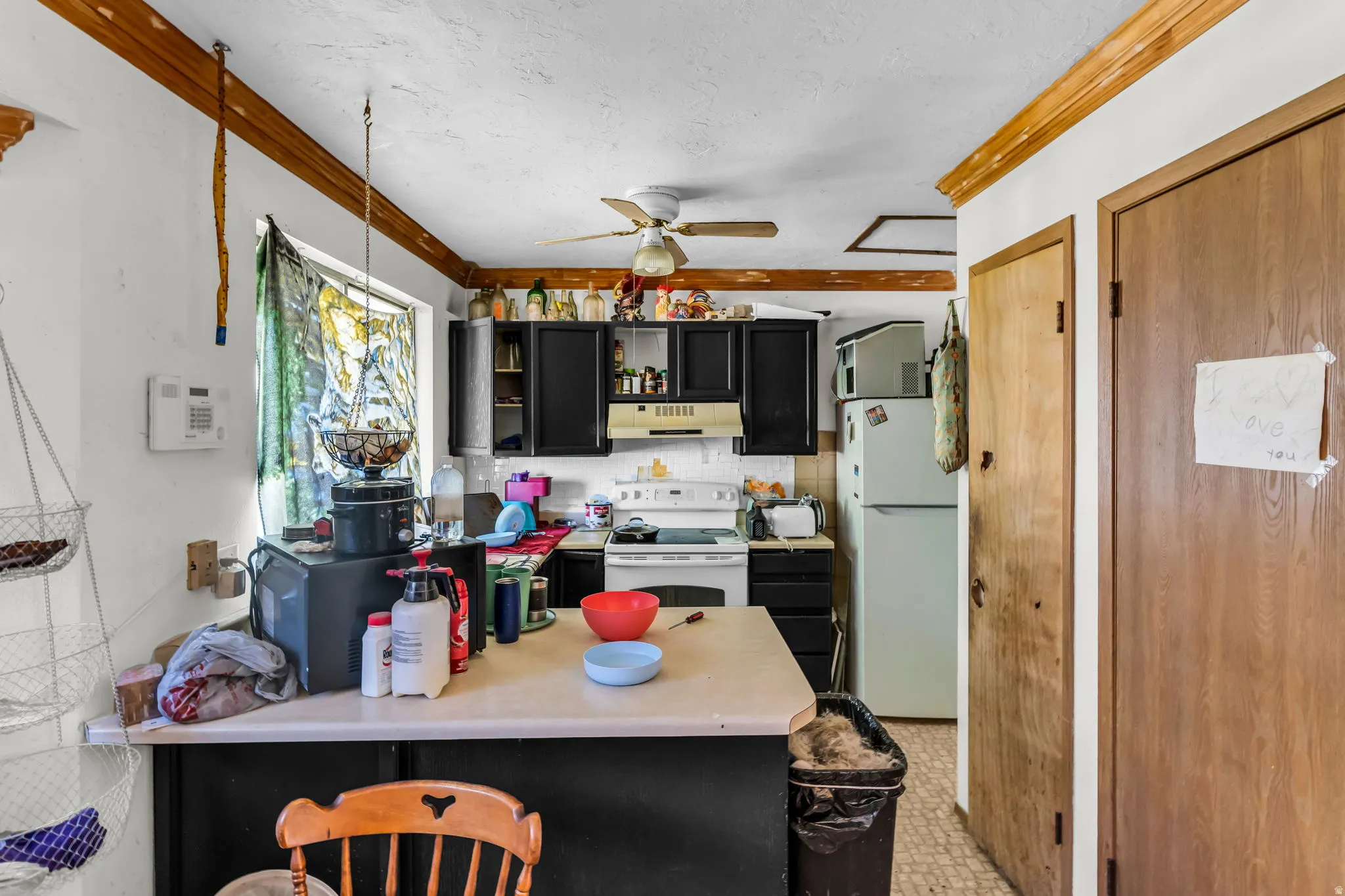 Kitchen featuring black cabinetry, a white appliance package, and a light-toned countertop