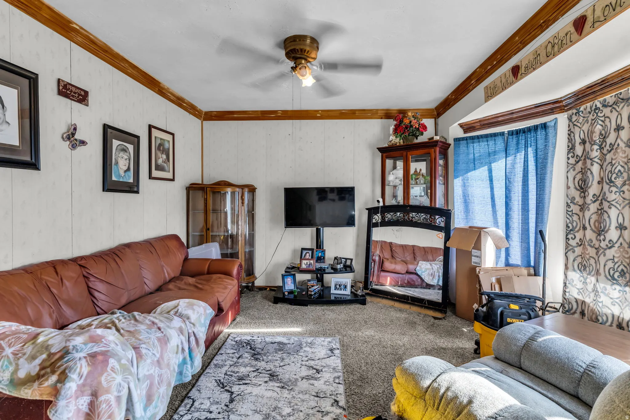 Living area featuring paneled walls with wood trim accents and a ceiling fan