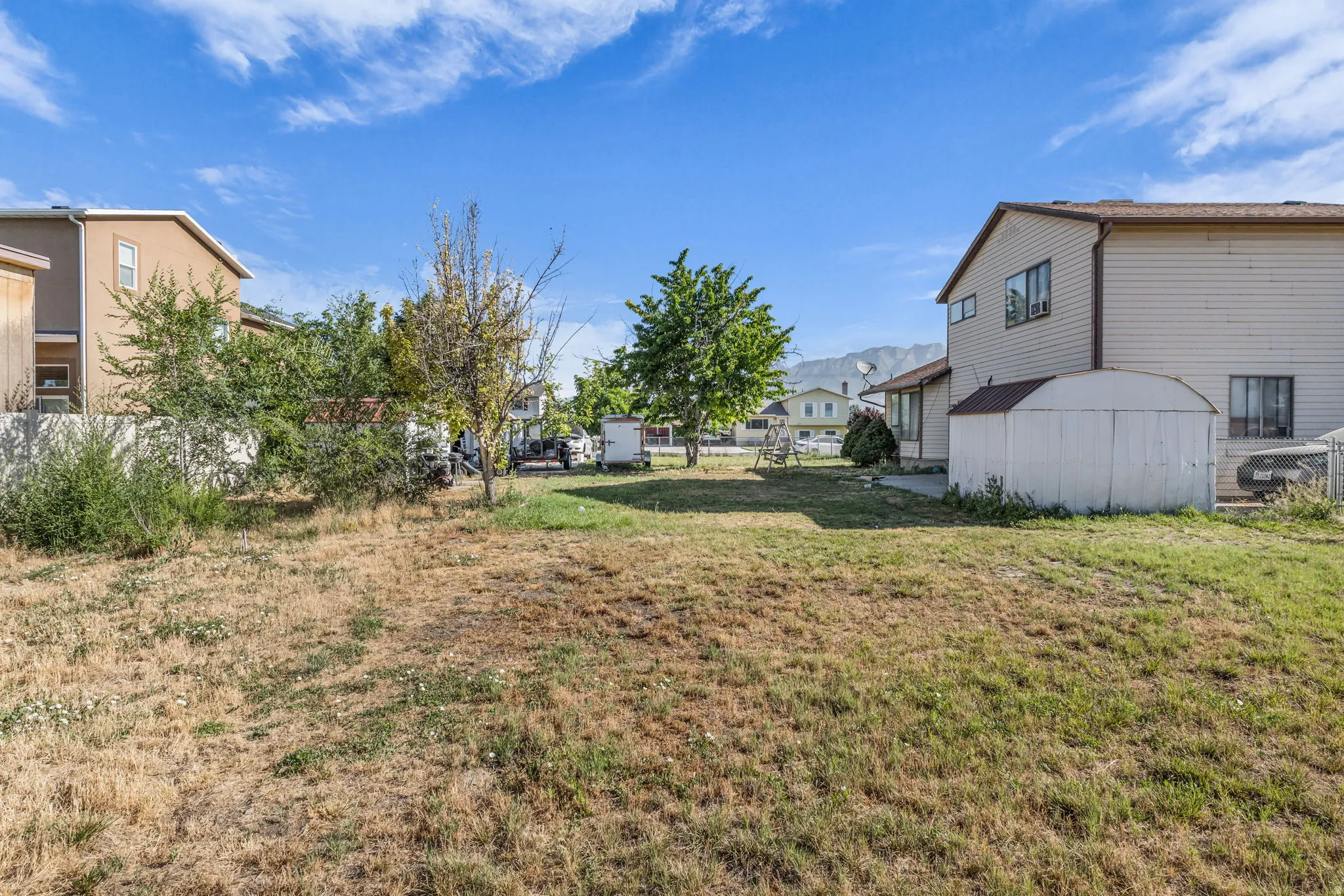 Expansive grassy yard with mountain backdrop and mature trees