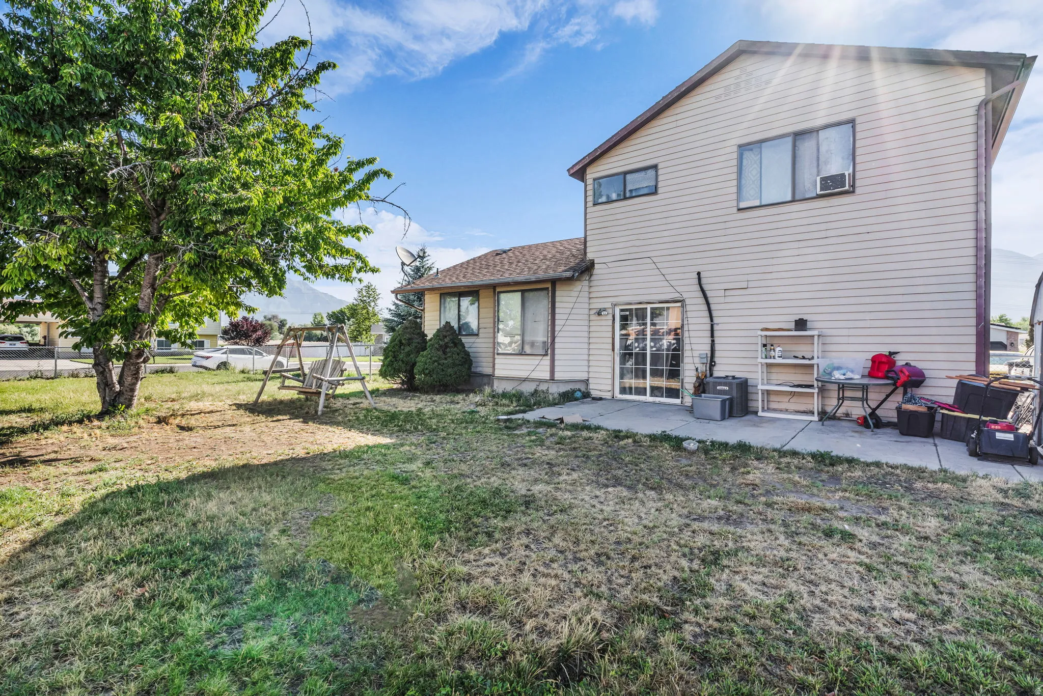 Exterior siding with multiple windows and a sliding glass door opening to a concrete patio