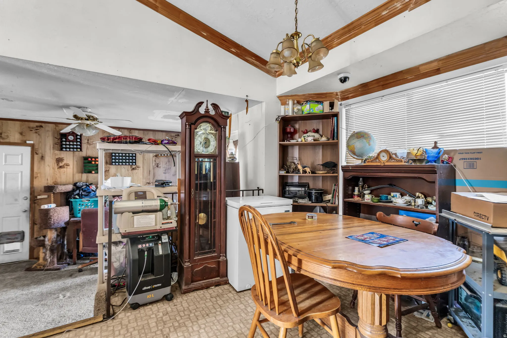 Dining area featuring a wood-finish oval table, chandelier lighting, and a large window with blinds