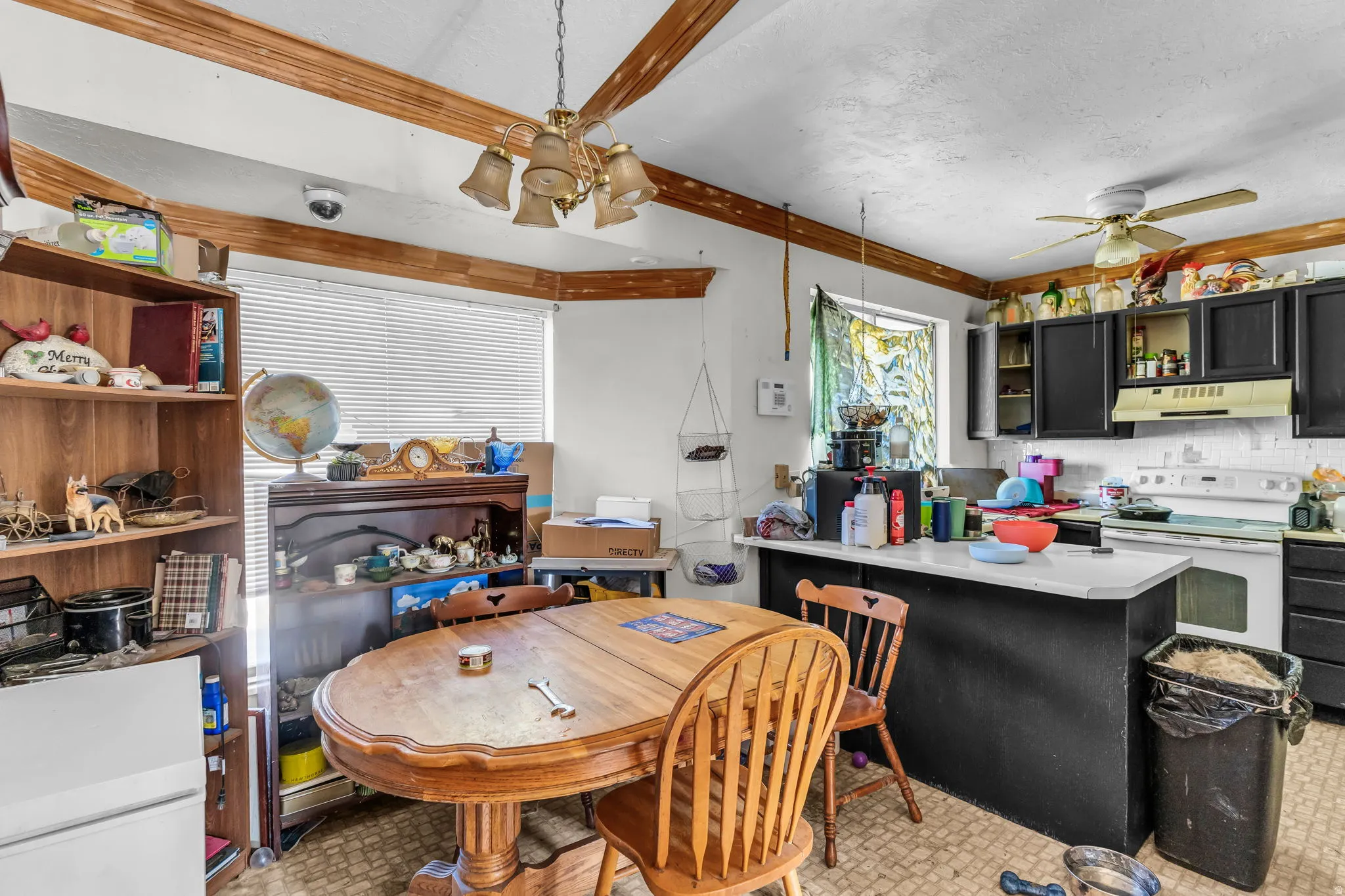 Kitchen area featuring wood-finish ceiling beams, a ceiling fan, and a chandelier