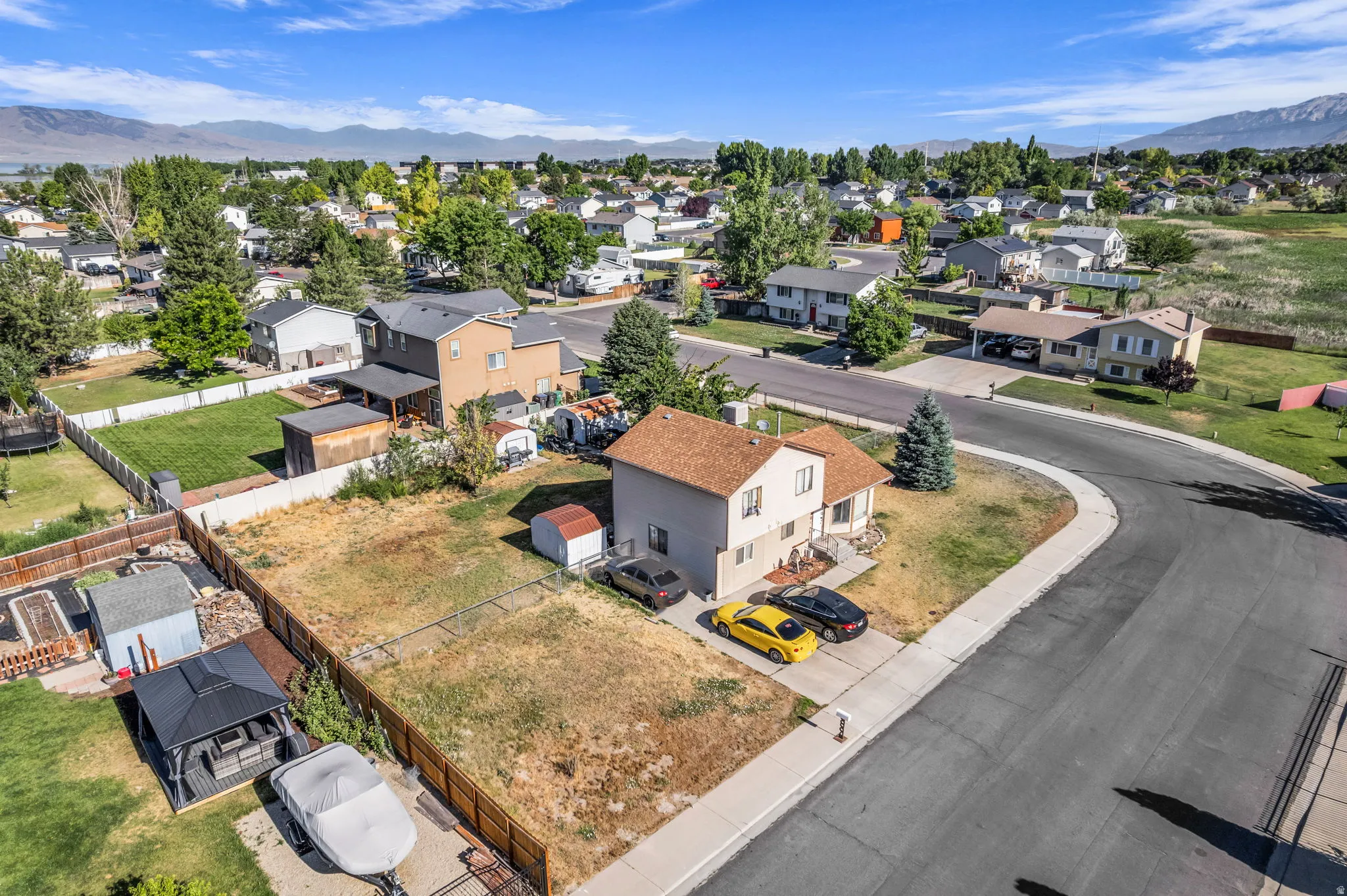 Residential lot featuring mature trees, a paved driveway, and established neighborhood infrastructure