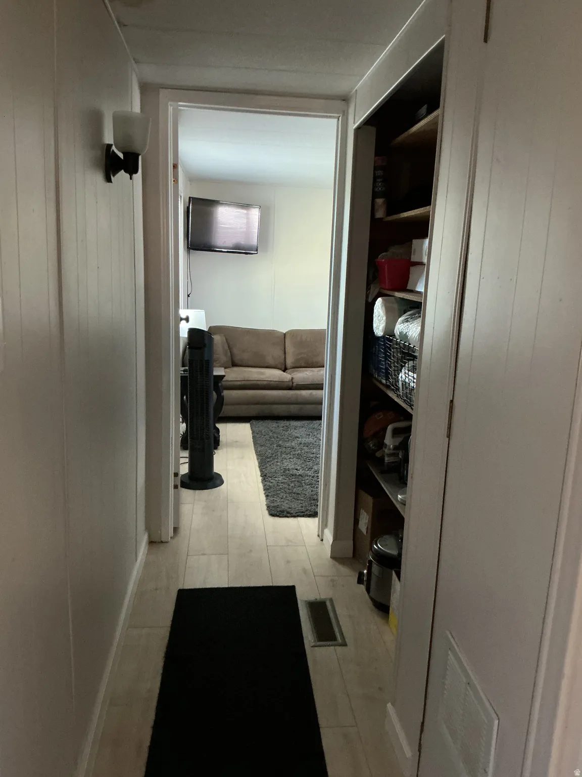 Hallway with wood-finish flooring and white panel walls