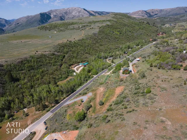 Expansive mountain landscape featuring a paved road, scattered residences, and extensive natural foliage