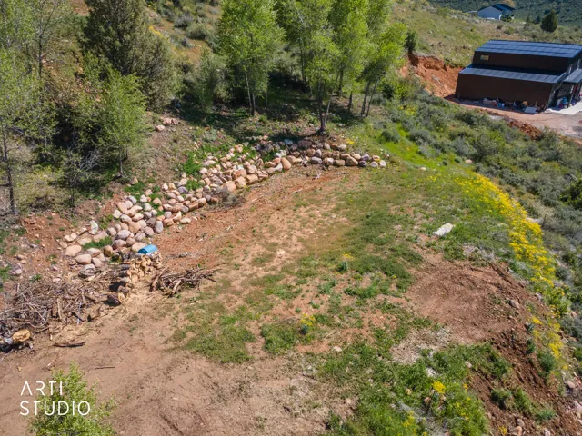 Expansive hillside property featuring established trees and a natural rock retaining wall