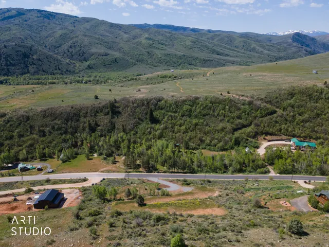Expansive mountain landscape featuring varied terrain with verdant hillsides and distant snow-capped peaks