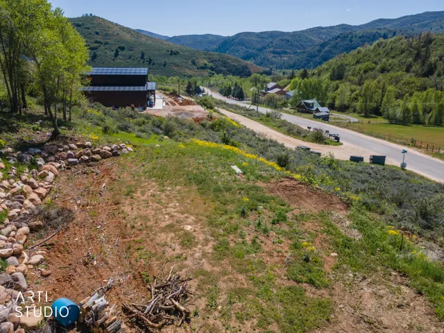 Expansive hillside property featuring a partially graded lot, established trees, and a rock retaining wall