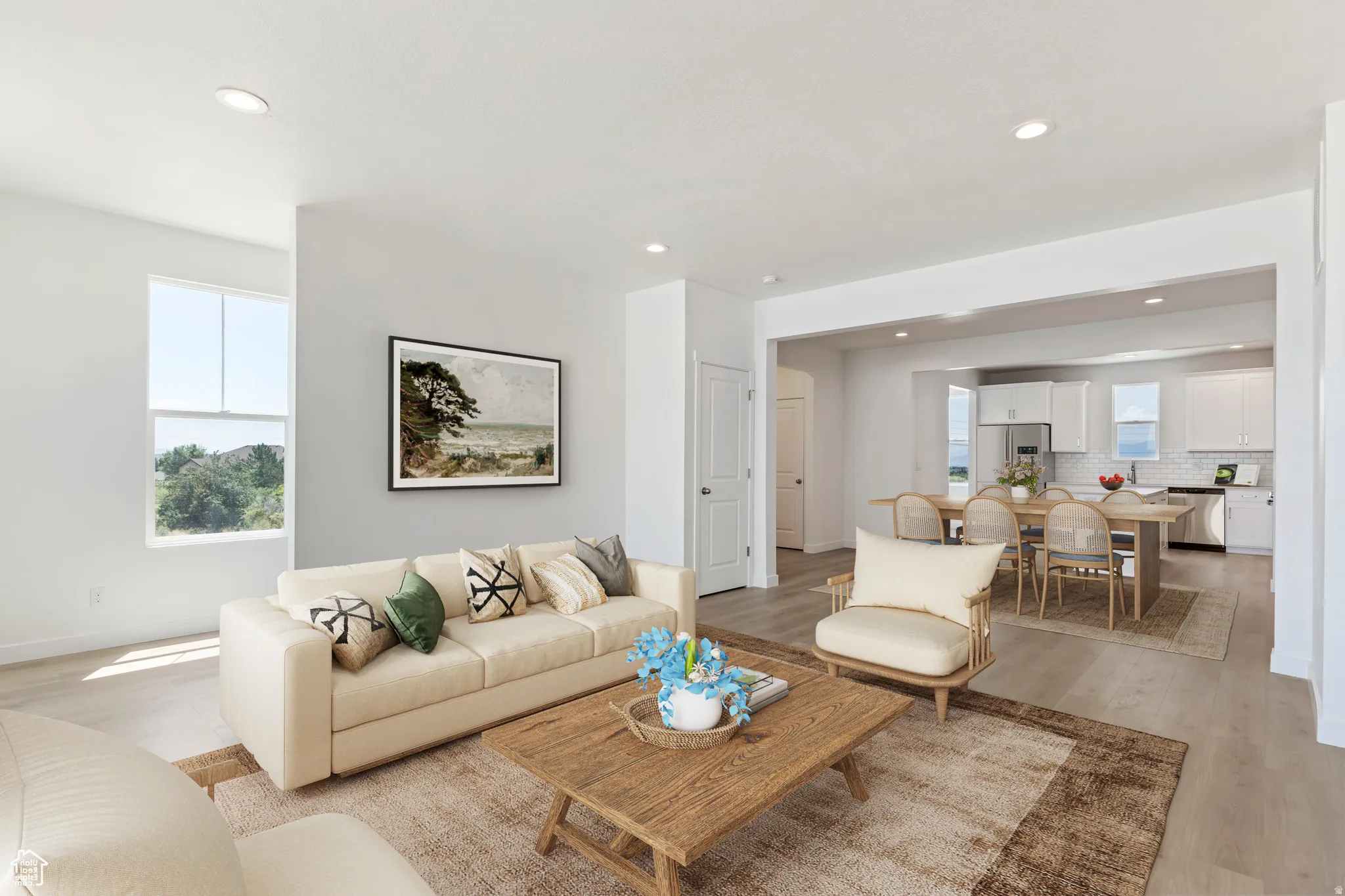 Open-concept living area featuring light wood-finish flooring, recessed lighting, and a neutral color palette