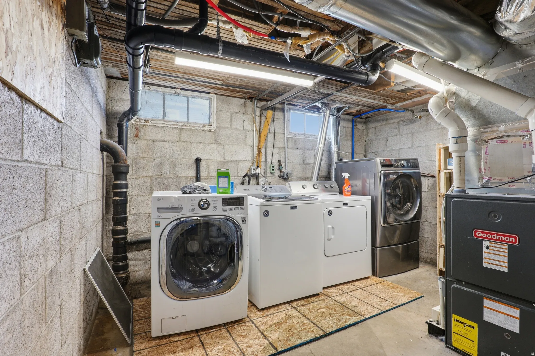 Dedicated utility area featuring a washer, dryer, furnace, hot water heater, and exposed ceiling joists
