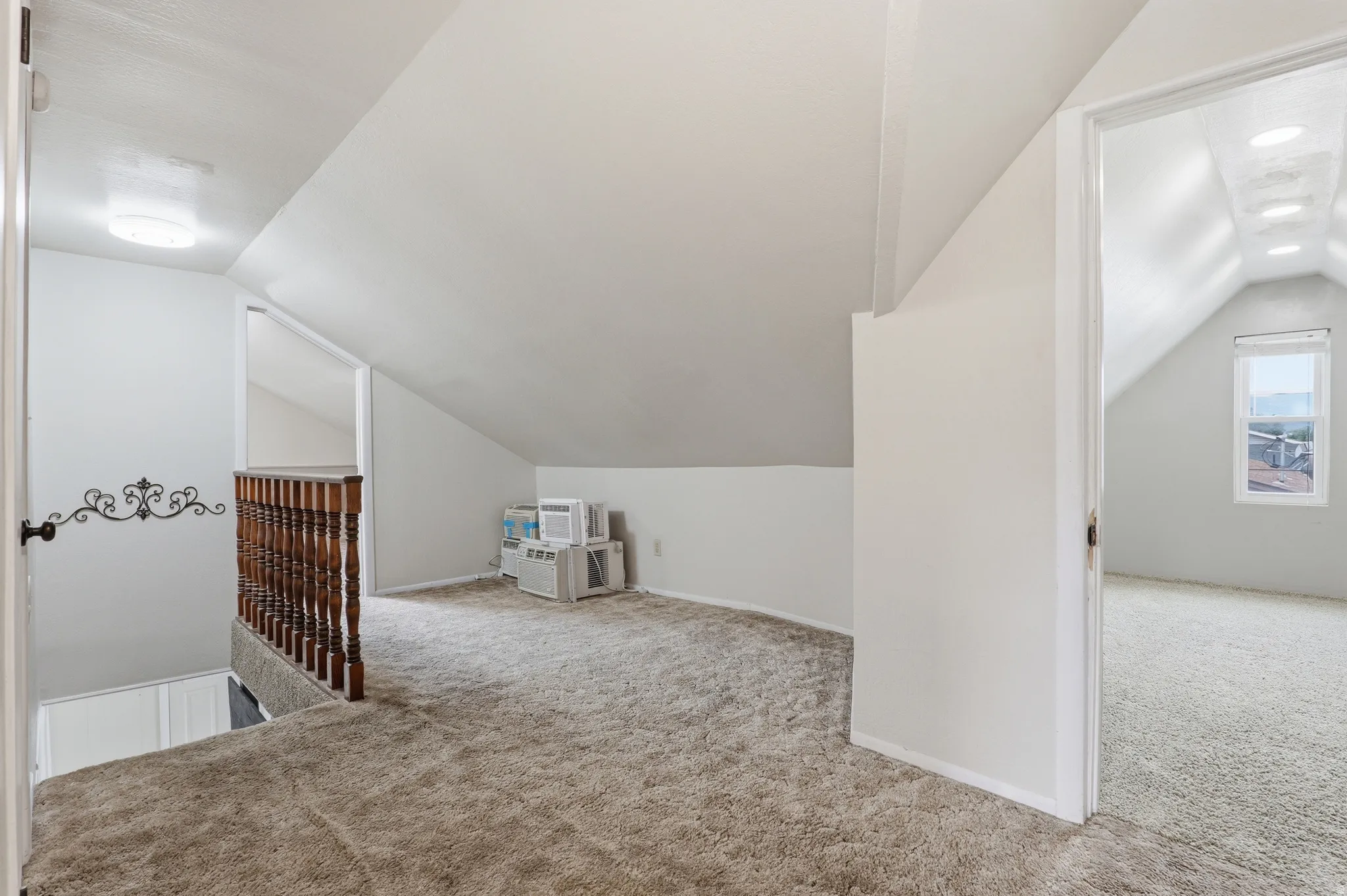 Carpeted loft area featuring a wooden spindle railing and sloped ceilings