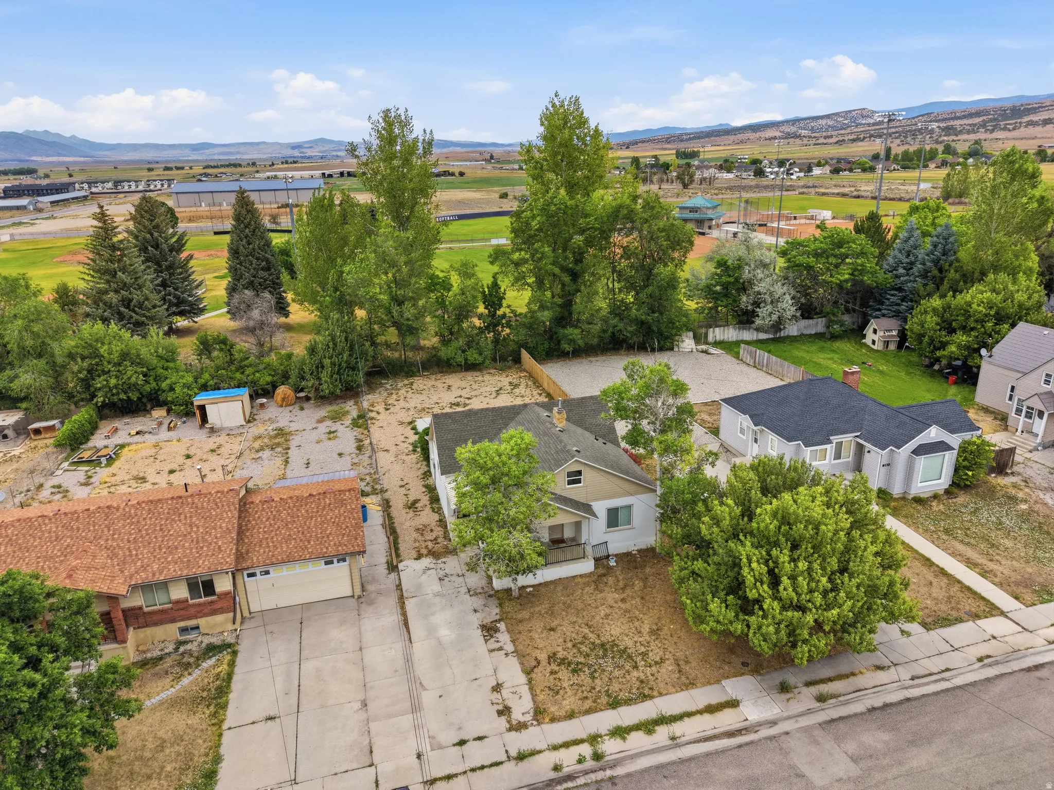 Aerial perspective showcasing multiple properties, extensive paved areas, and distant mountainous scenery