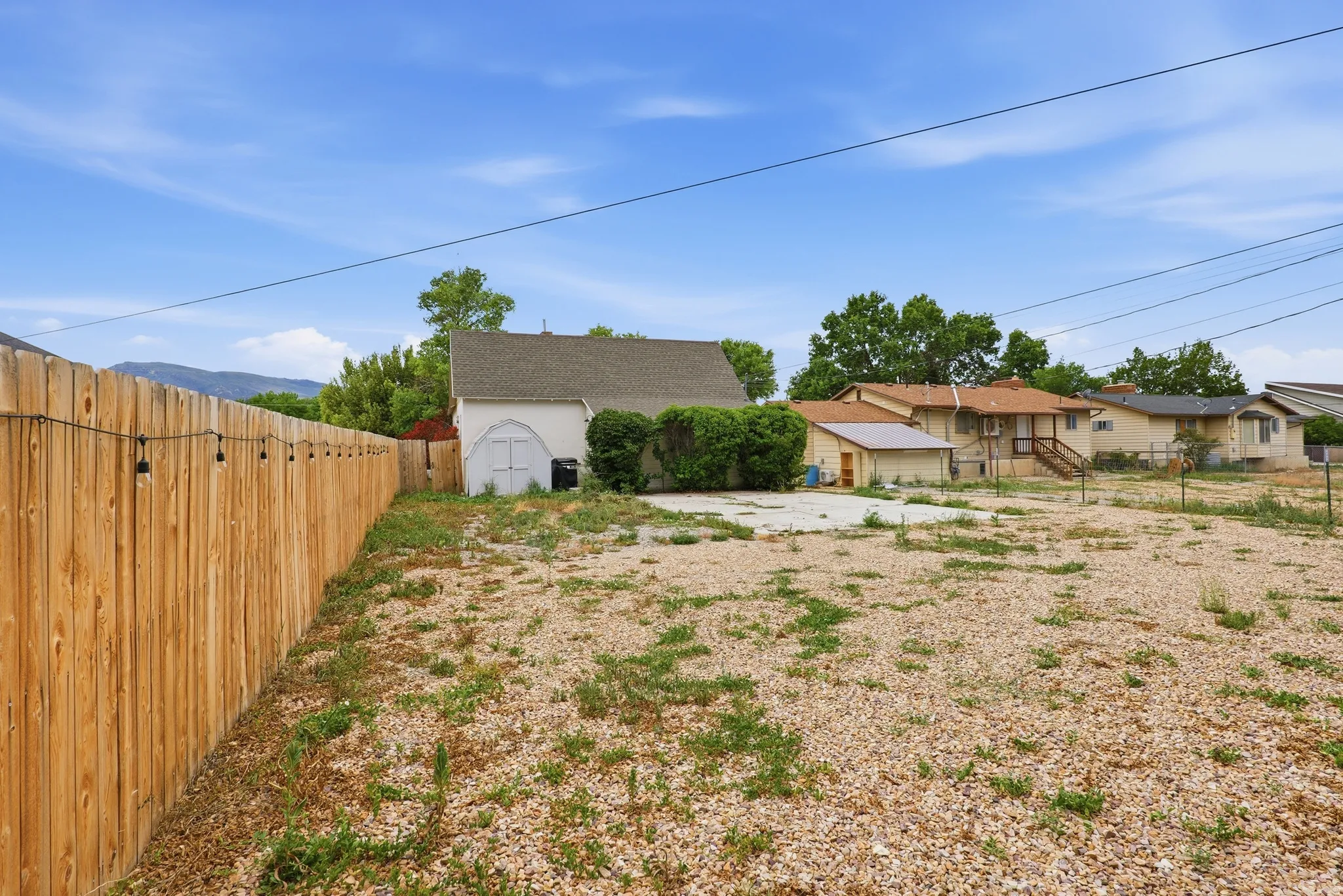 Spacious gravel lot featuring a new privacy fence with string lighting