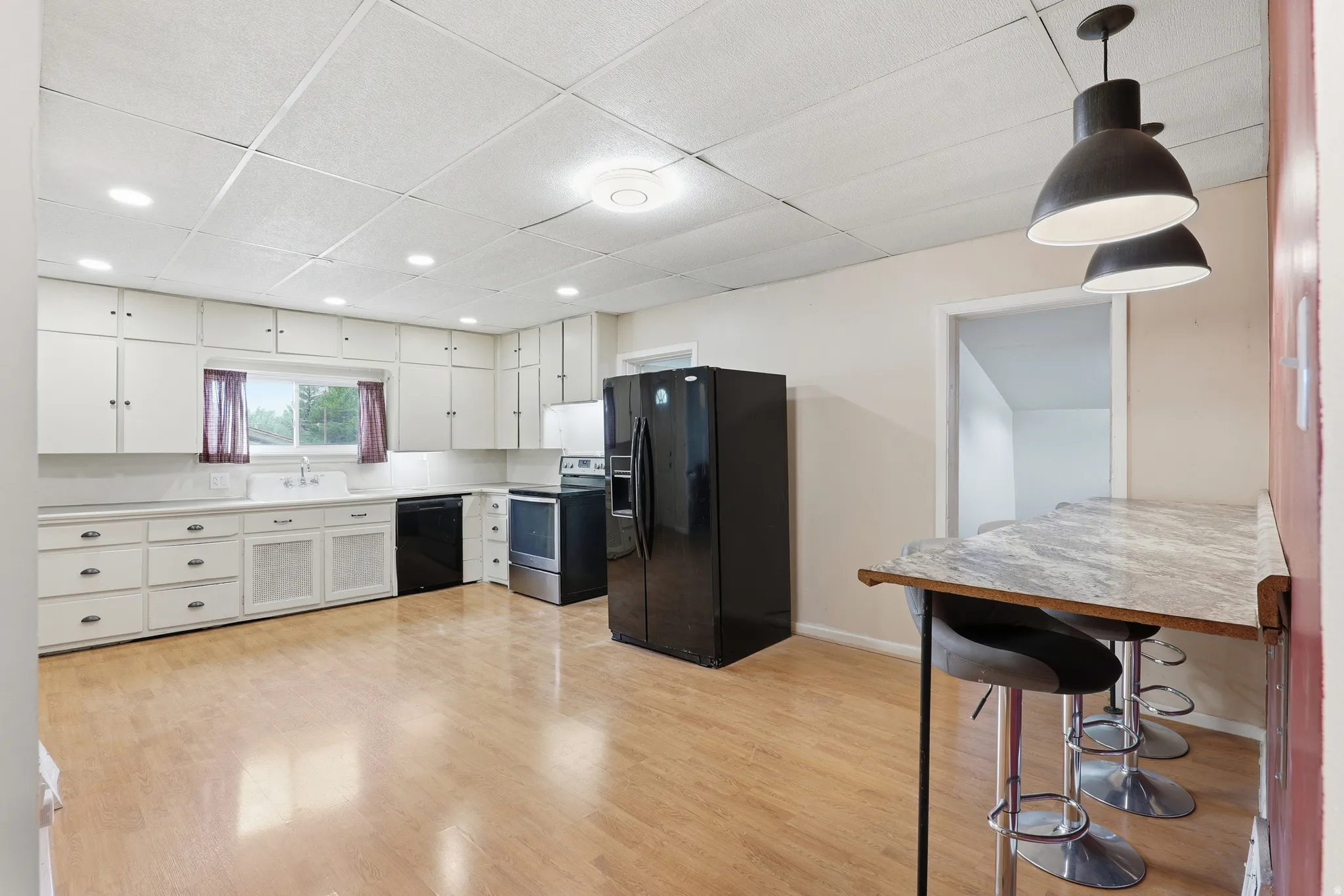 Kitchen featuring extensive white cabinetry, wood-finish flooring, and black appliances