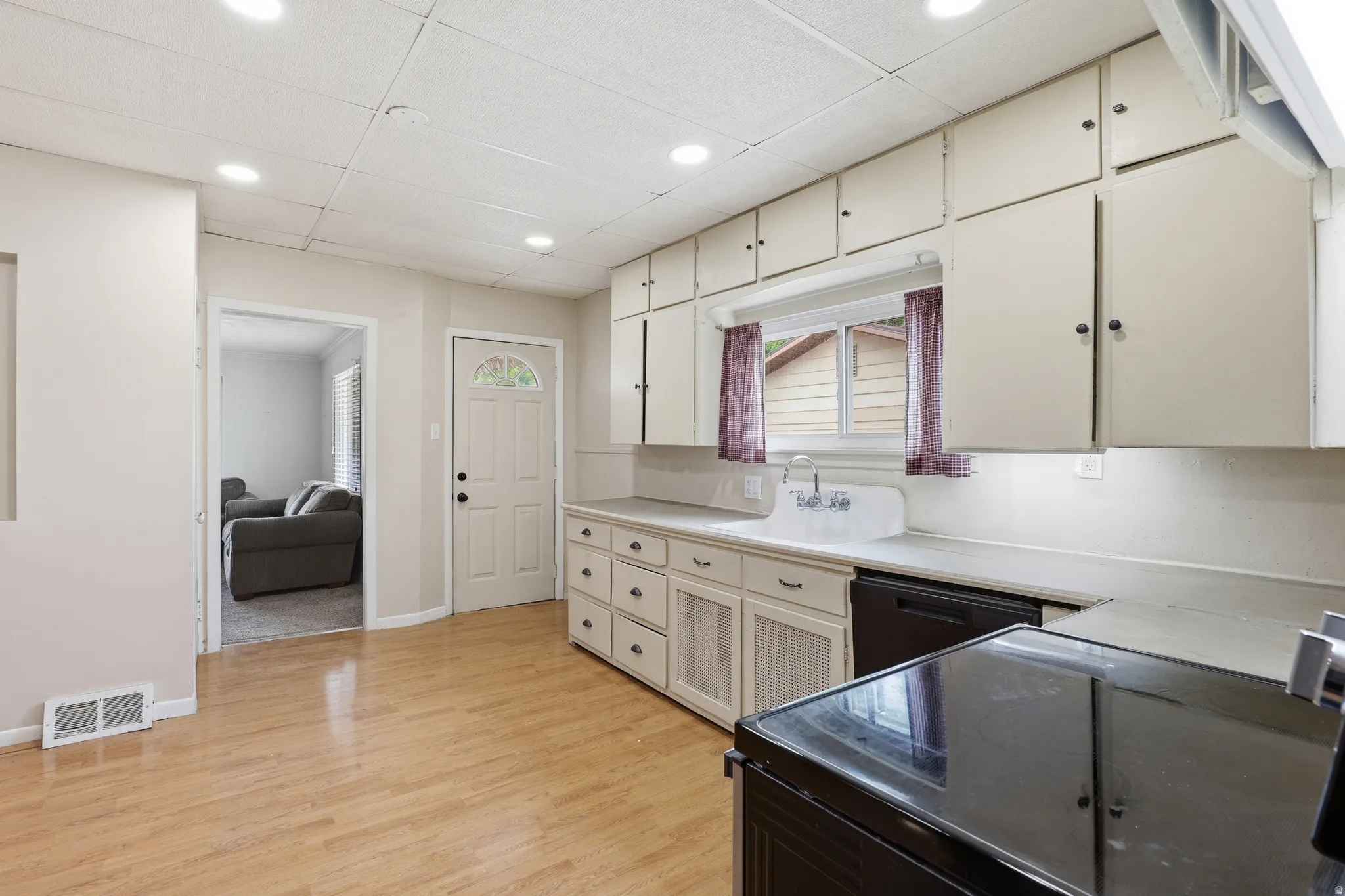 Kitchen featuring wood-finish flooring, recessed lighting, white cabinetry, integrated sink, and an exterior door with an arched window