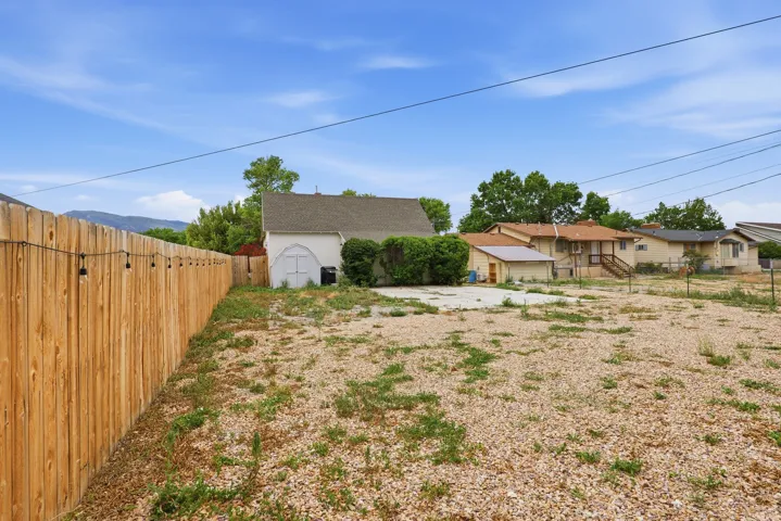 Spacious gravel lot featuring a new privacy fence with string lighting