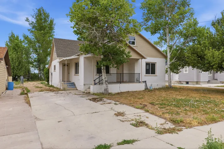 Two-story residence featuring a covered front porch with black metal railing, concrete driveway, and a partially covered entry