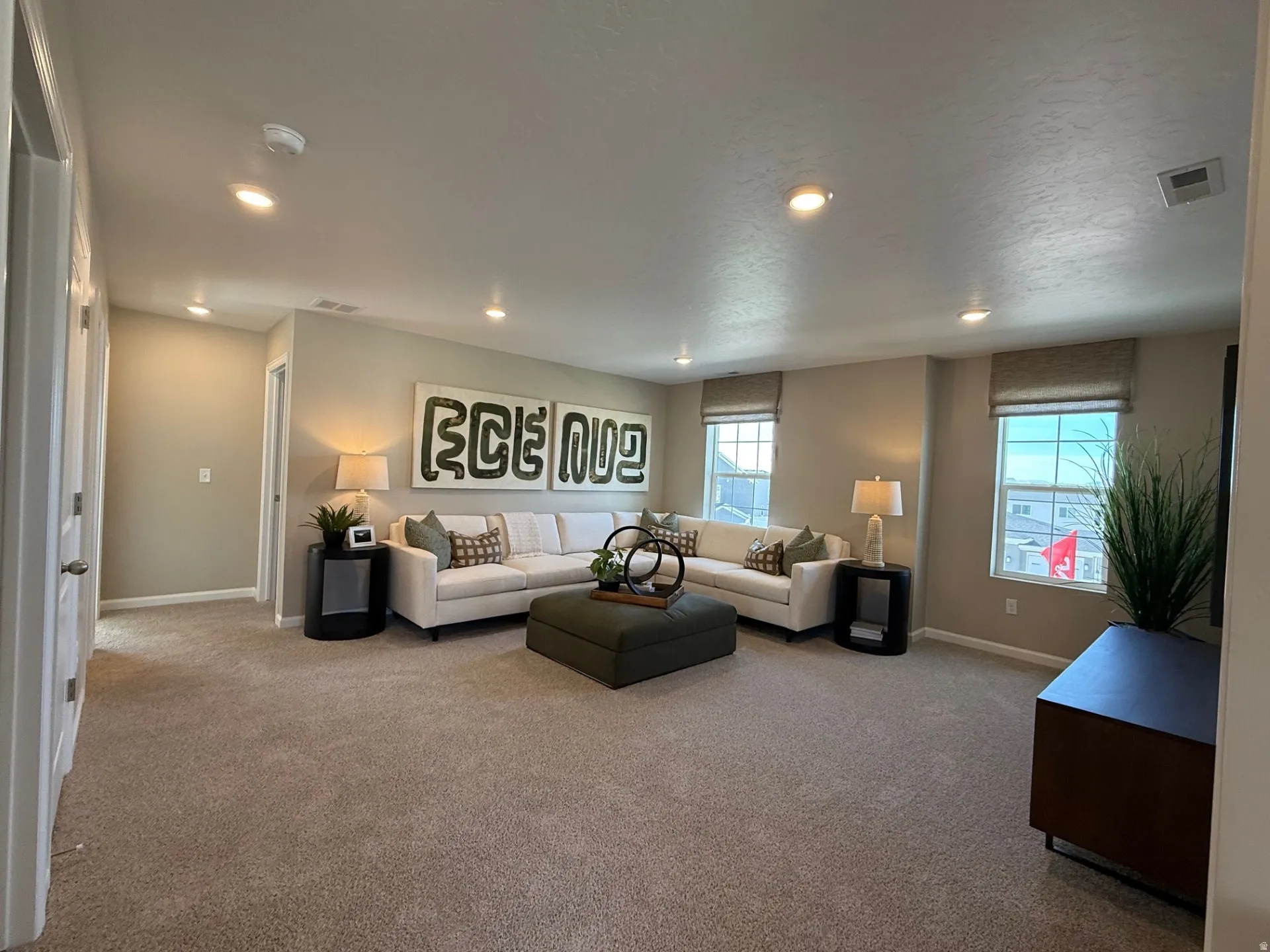 Carpeted living area featuring recessed lighting, multiple windows with blinds, and neutral wall tones