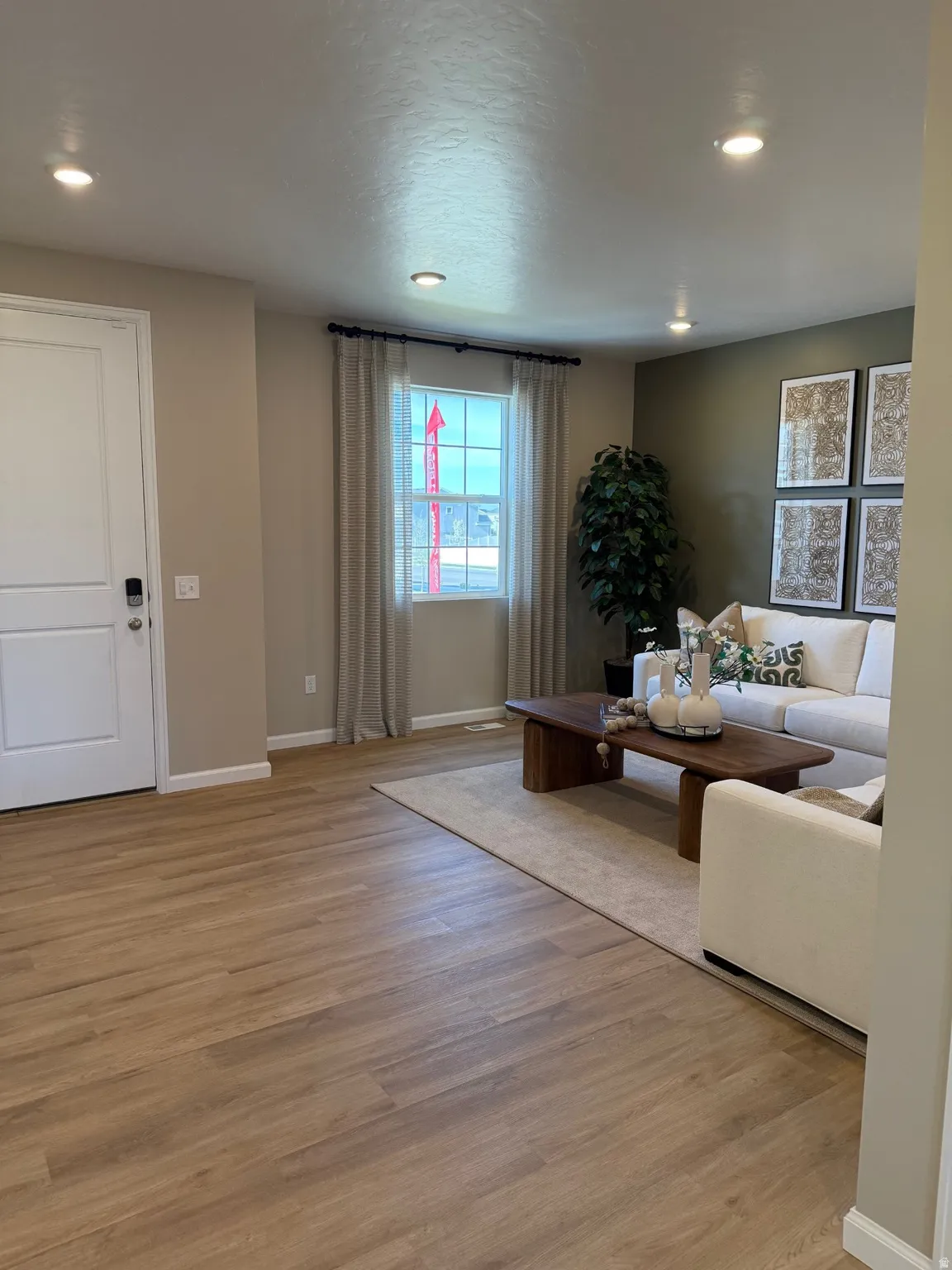 Open-concept living space with wood-finish flooring, recessed lighting, and a neutral color palette