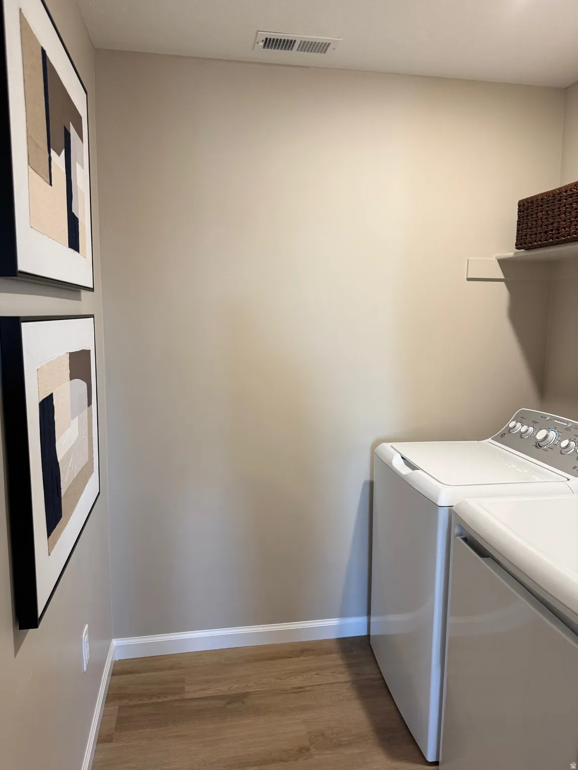 Dedicated utility area featuring wood-finish flooring, light tan wall color, and a built-in wall shelf