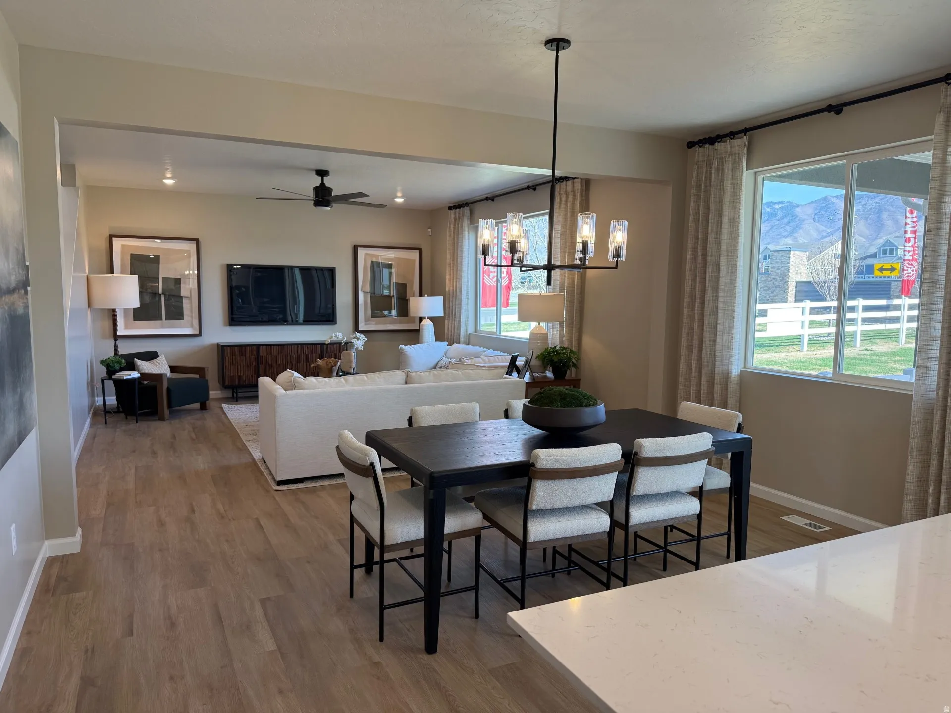 Open-concept common area featuring wood-finish flooring, a contemporary chandelier, and large windows with mountain scenery