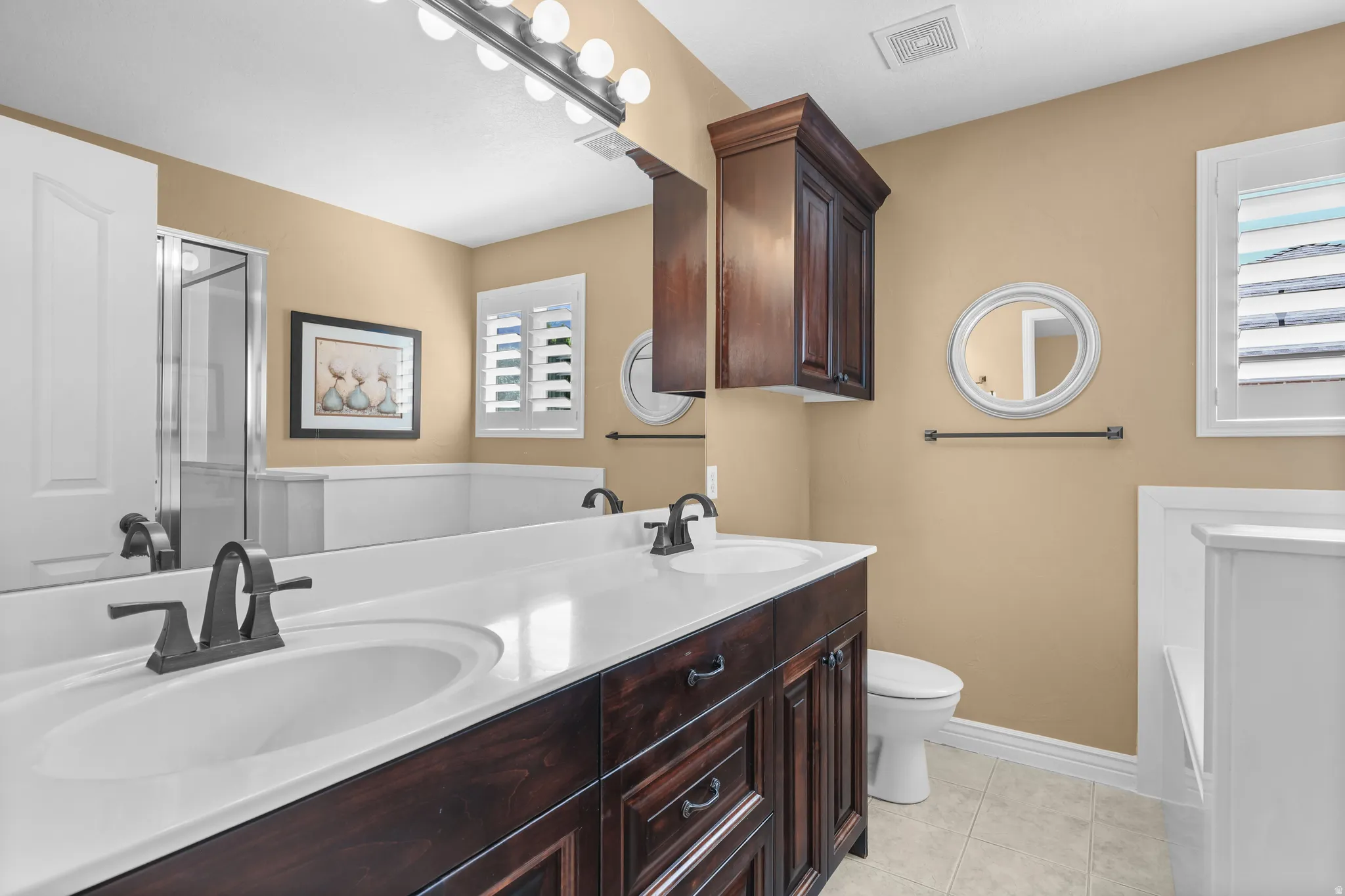 Double vanity with dark wood cabinetry and white countertops