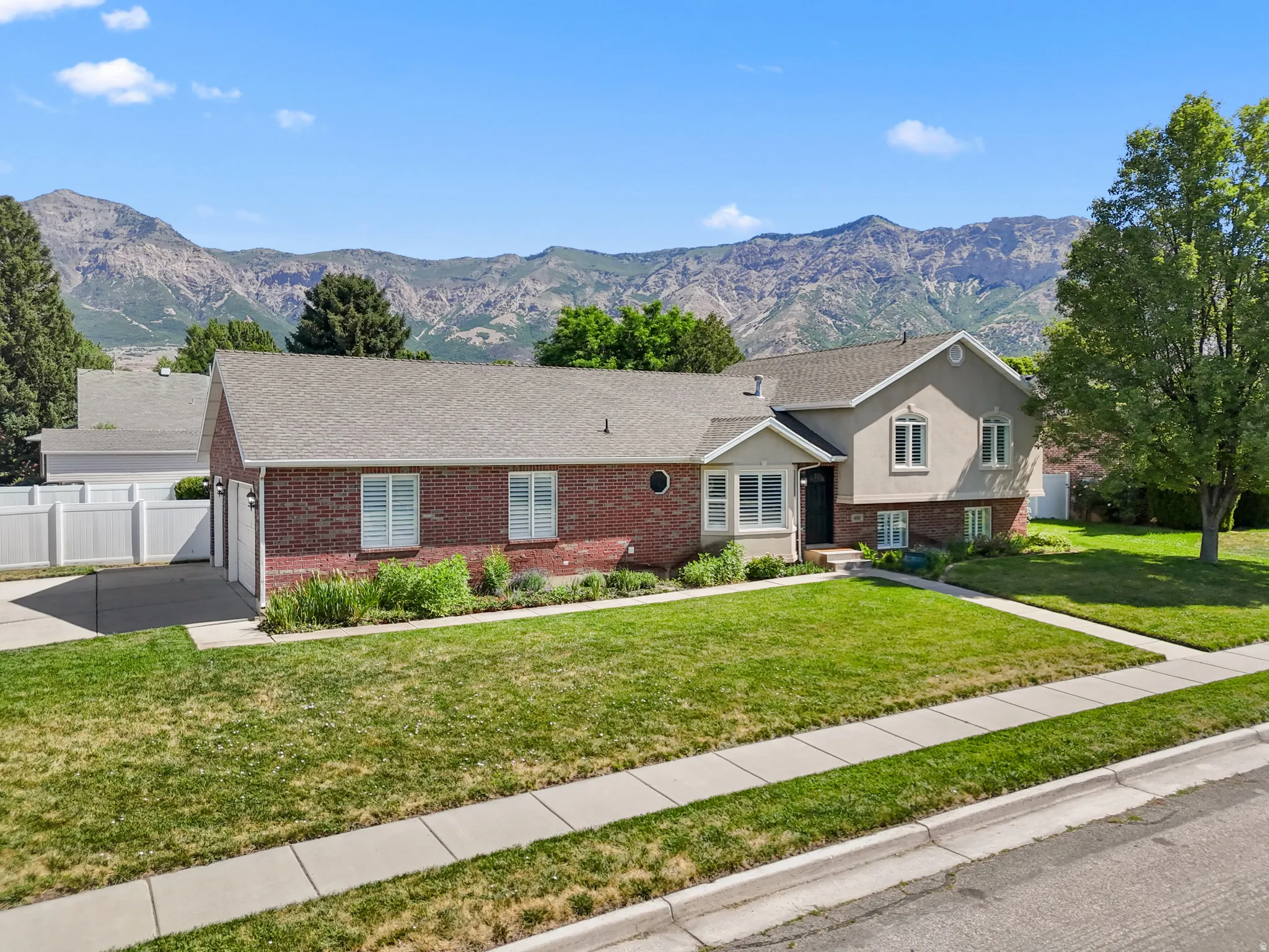 Brick and stucco exterior residence featuring a front lawn and paved driveway