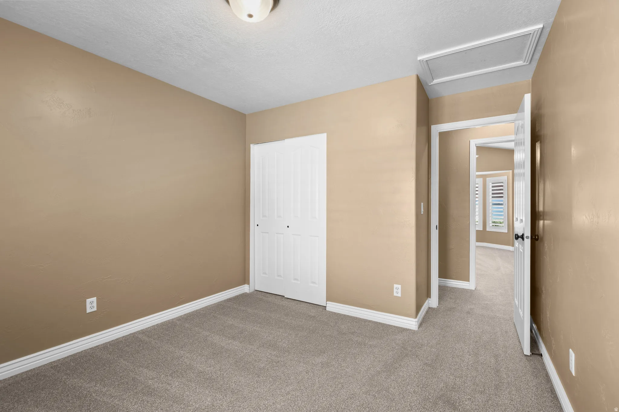 Carpeted room with neutral wall tones and white baseboards